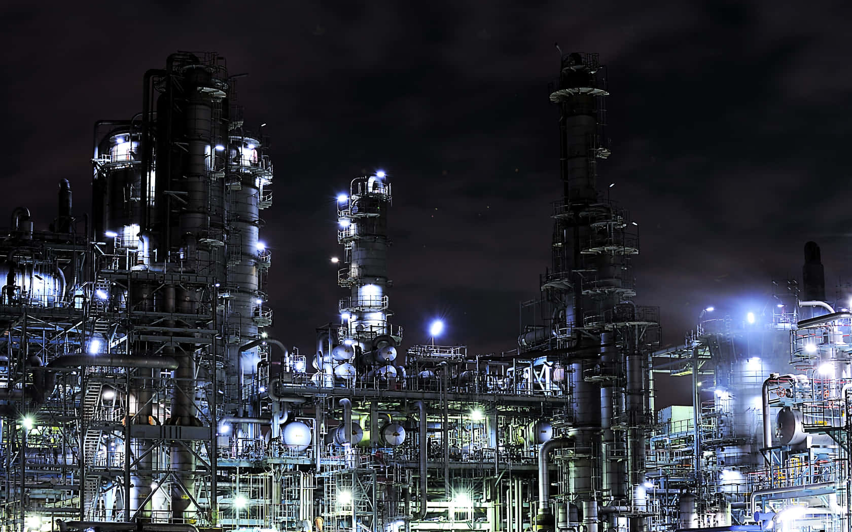 Oil 桌布 壁紙 — 一個龐大的工業煉油廠綜合體在漆黑的夜空下閃爍著人造燈光。