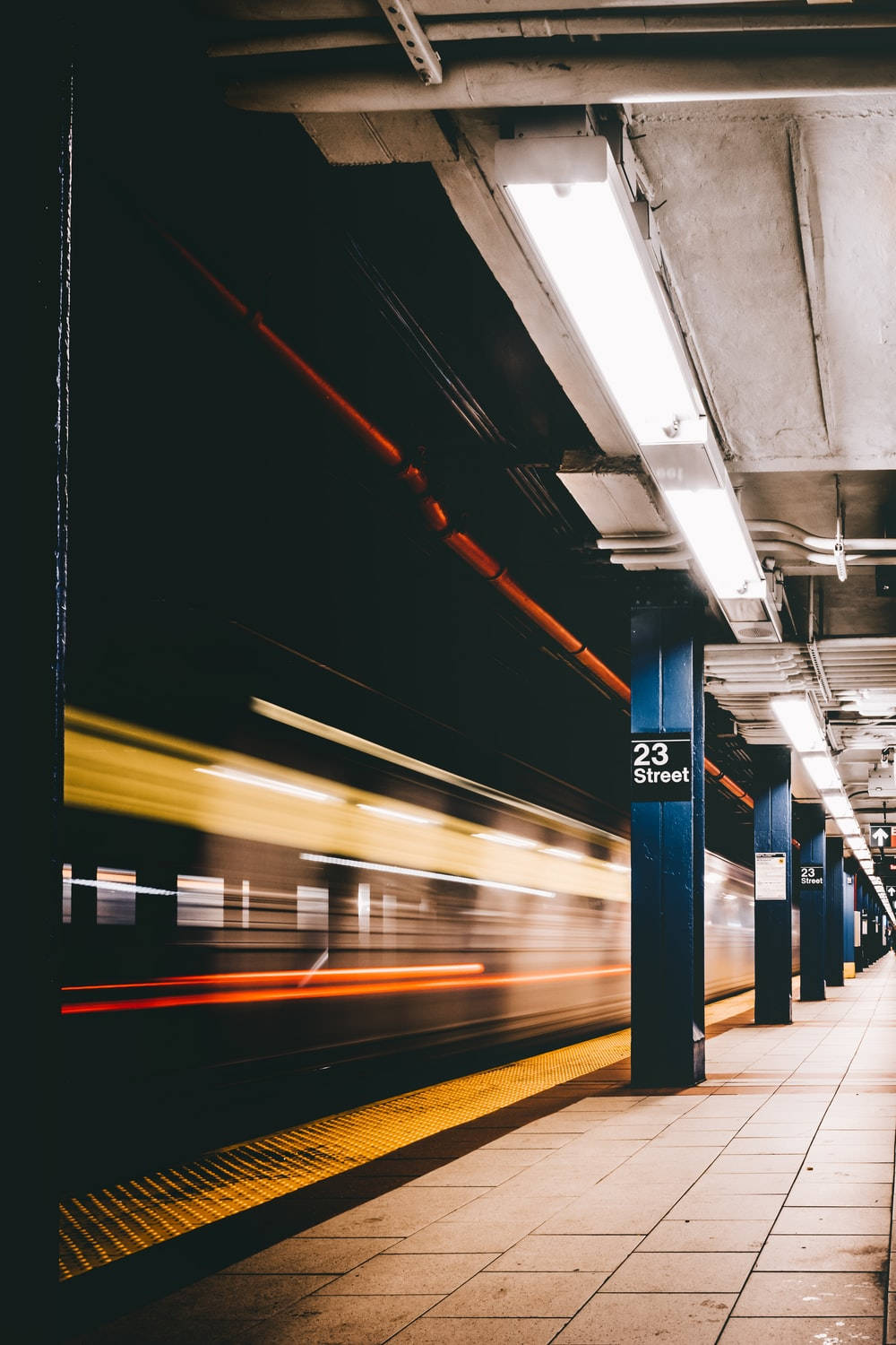 Subway 桌布 壁紙 — 一列地鐵火車在標有 23 Street 的昏暗車站月台上疾馳而過，留下動態模糊的光跡。