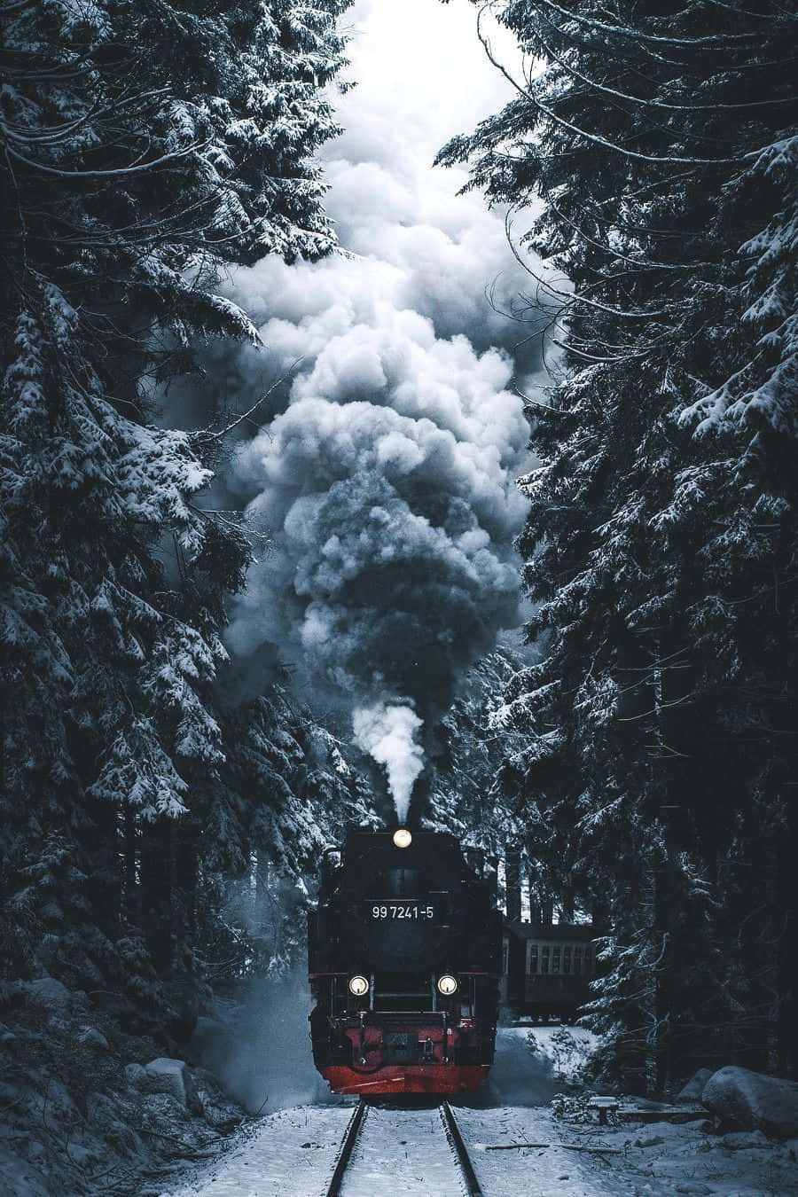 冬季美學 桌布 壁紙 — 一列帶有紅色裝飾的蒸汽火車穿過白雪覆蓋的森林，向冬日空氣中釋放出濃煙。