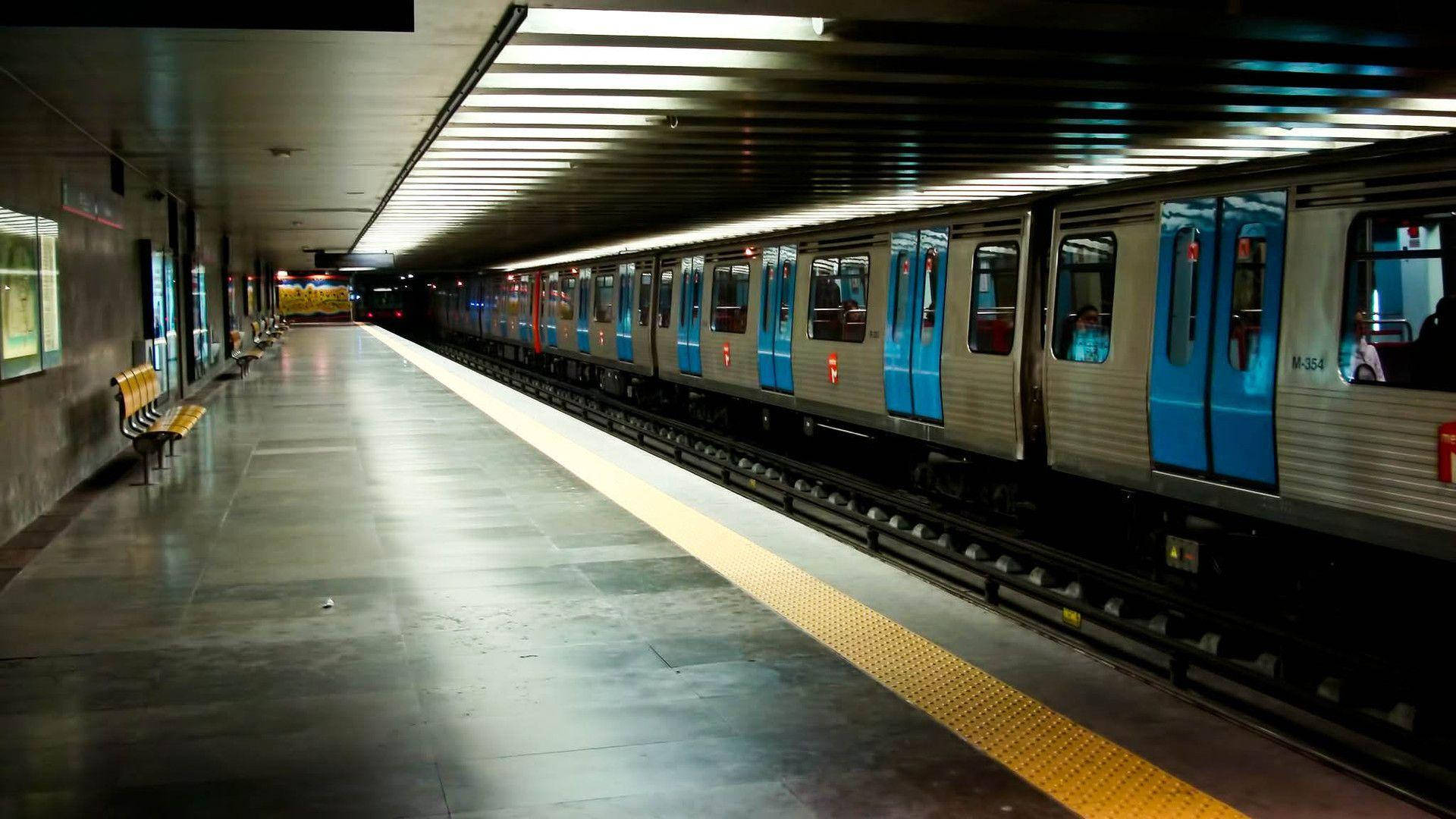 Subway 桌布 壁紙 — 一列時尚的地鐵列車，藍色車門，停在光線昏暗的地下車站月台上，月台標有黃色安全線。