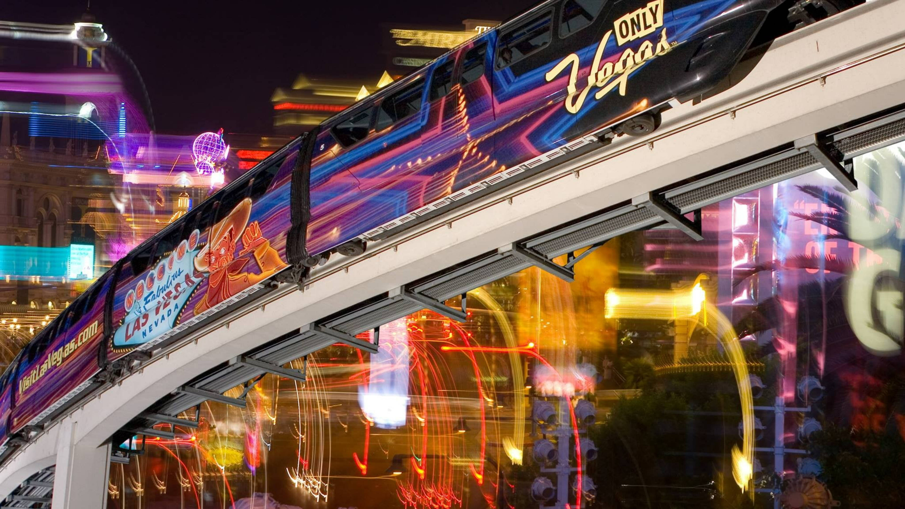 拉斯維加斯 桌布 壁紙 — 一列標有「ONLY Vegas」的單軌列車在燈火輝煌的拉斯維加斯大道上滑行，伴隨著色彩繽紛的霓虹燈條紋，充滿活力的夜景。