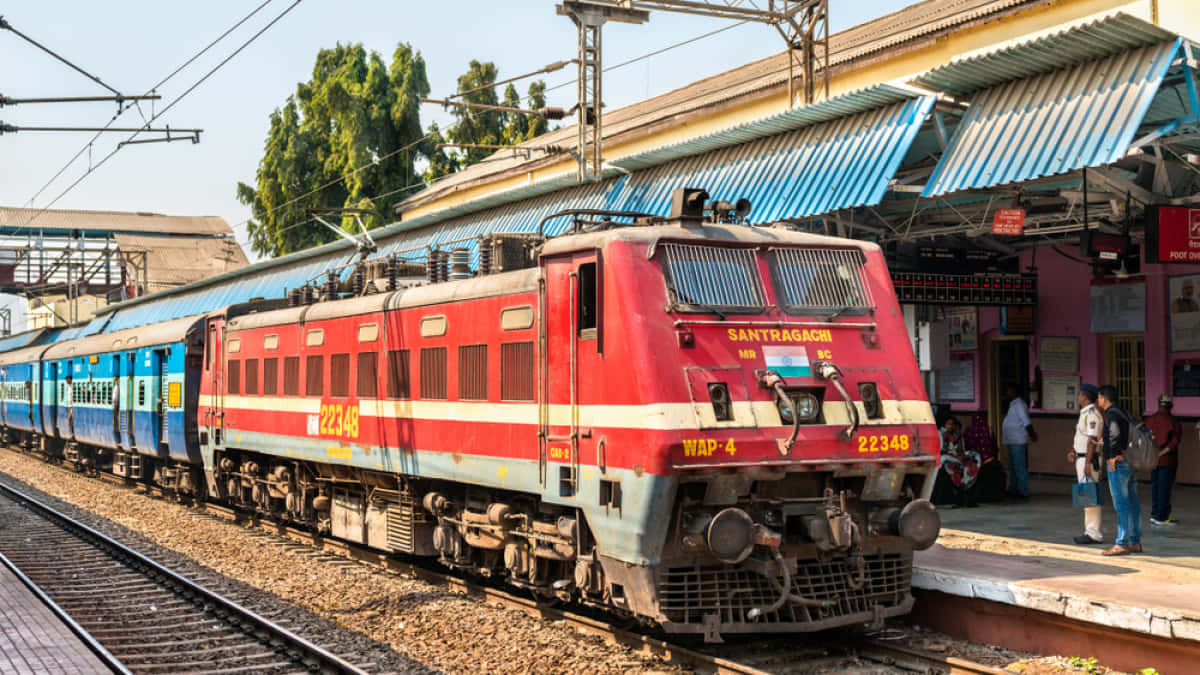 Indian Railway 桌布 壁紙 — 一列標有Santragachi的紅藍色印度客運列車在繁忙的車站月台上停靠，天空湛藍。