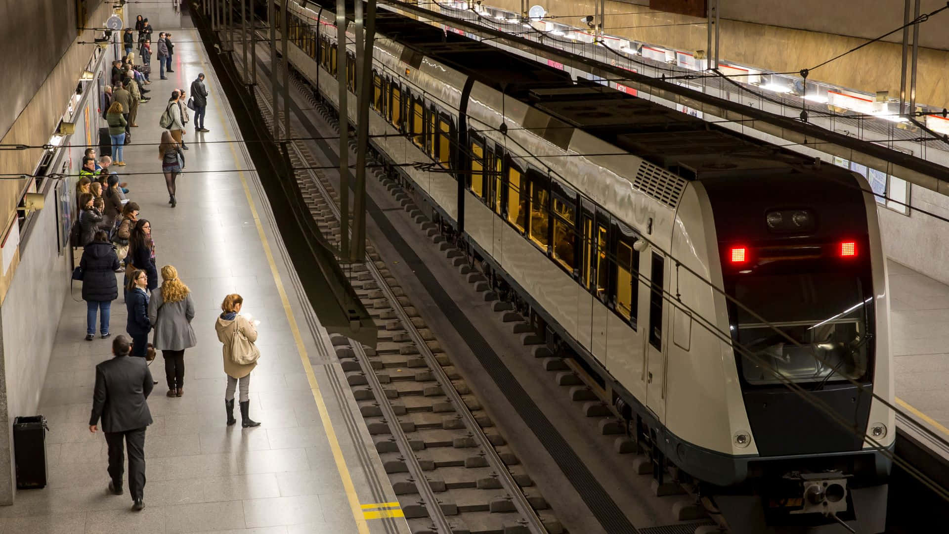 地鐵 桌布 壁紙 — 一列現代地鐵列車到達繁忙的地下車站，乘客在月台上等候。