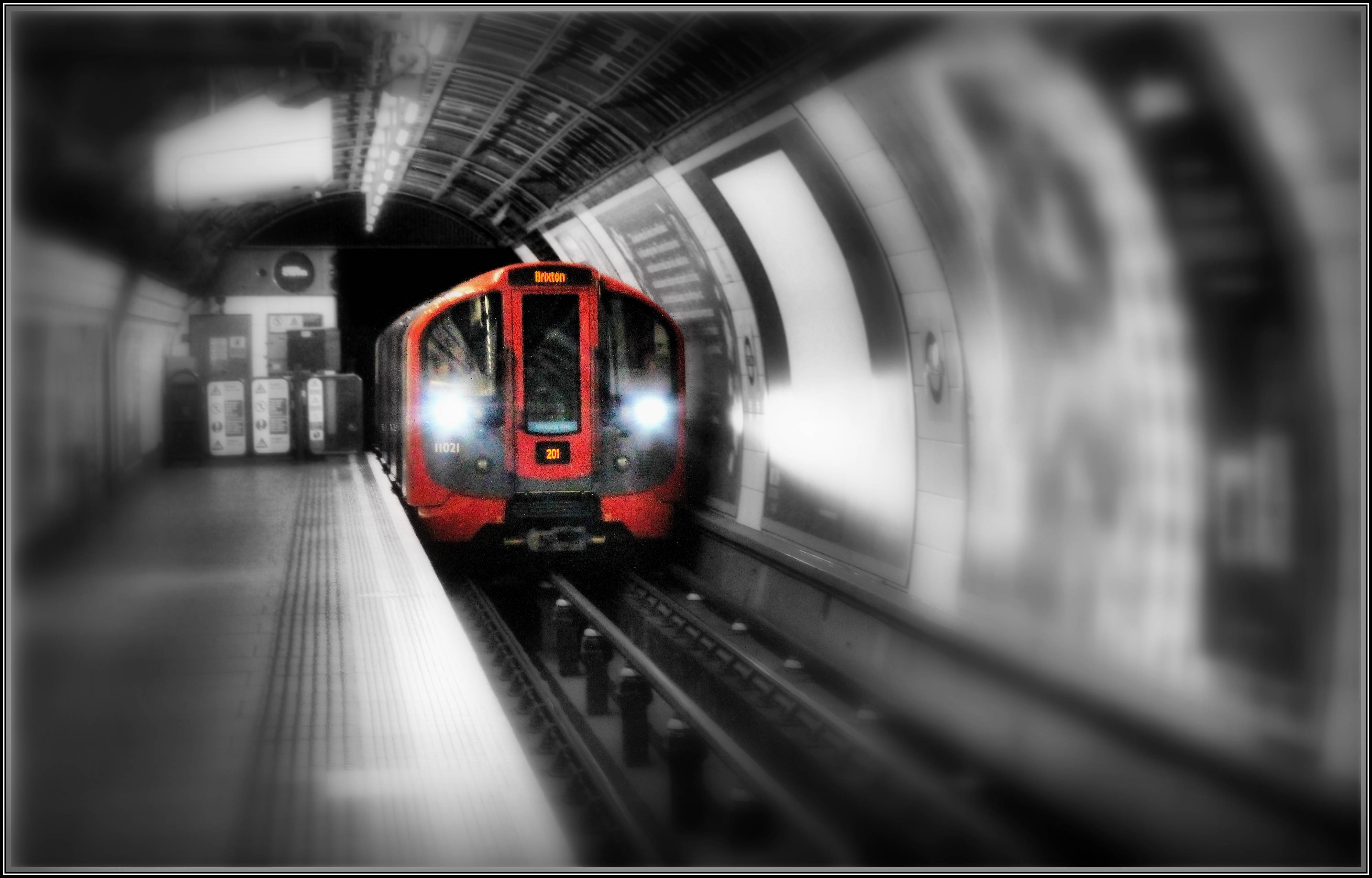 Subway 桌布 壁紙 — 一列紅色火車亮著明亮頭燈，在淺景深和黑白背景下接近地鐵月台。