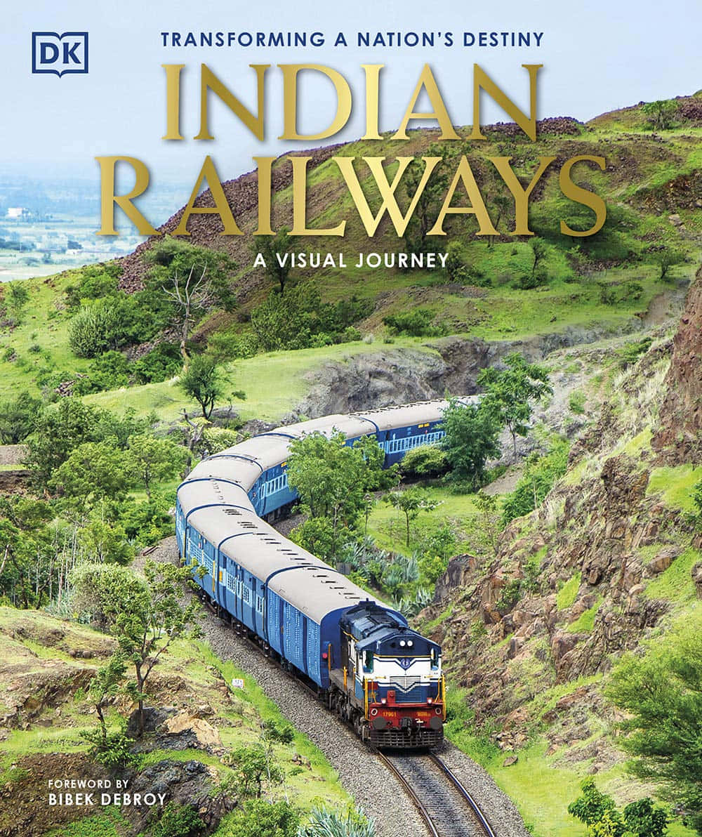 Indian Railway 桌布 壁紙 — 一列藍色的印度鐵路火車在晴朗的天空下蜿蜒穿過鬱鬱蔥蔥的綠色山丘和岩石地形。