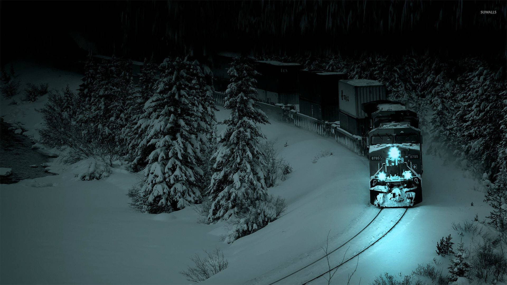 風景 桌布 壁紙 — 一列被雪覆蓋的貨運火車，車頭燈閃爍，在夜晚穿過黑暗的冬季森林。