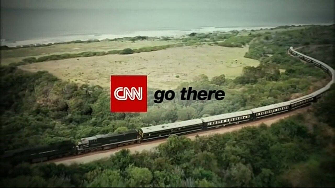 Cnn 桌布 壁紙 — 一列長長的火車蜿蜒穿過茂密的綠色森林，在陰天之下駛向遠方的大海。