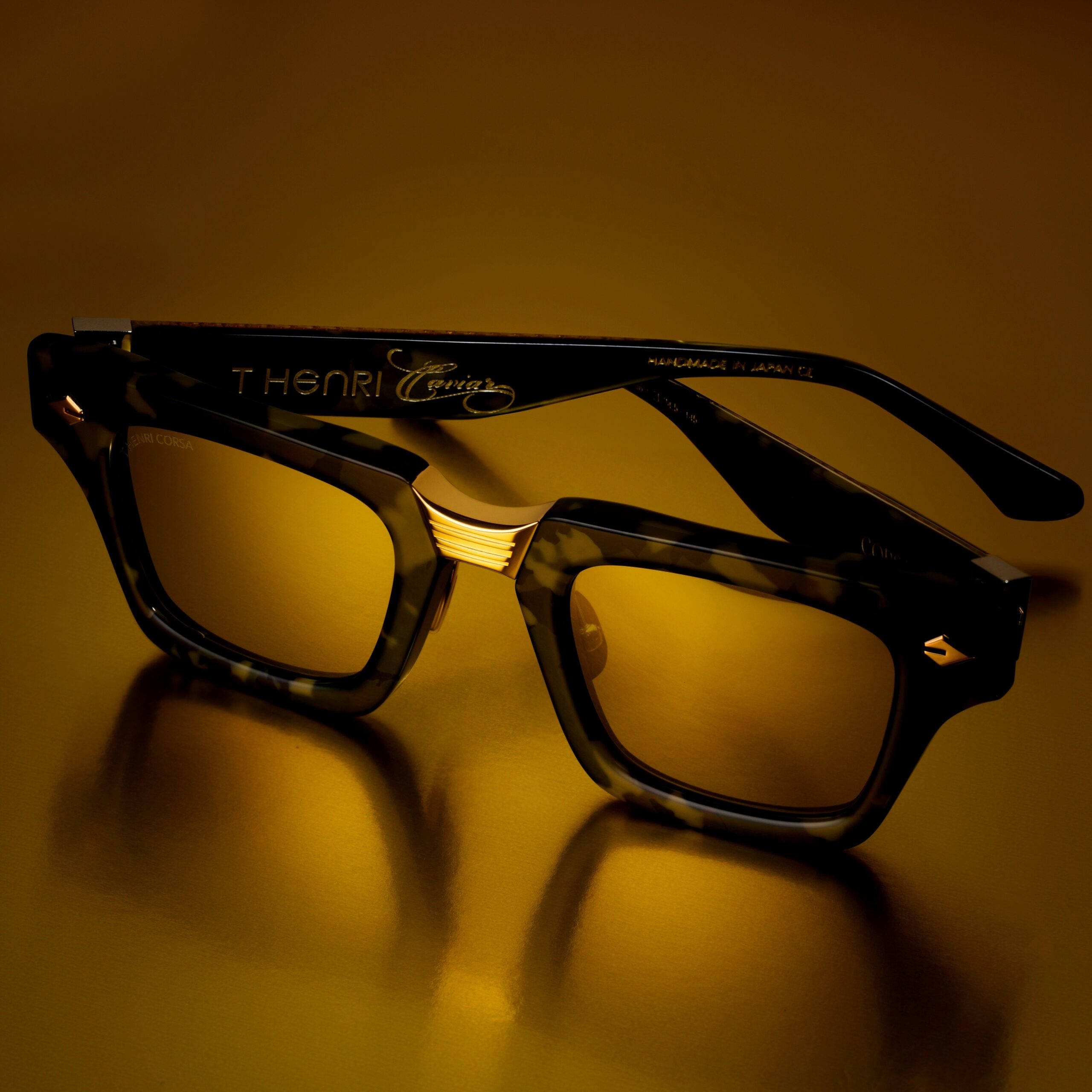 glasses 桌布 壁紙 — 一副帶有金色點綴的玳瑁太陽眼鏡，在柔和的方向性燈光下，放置在溫暖的金色表面上。