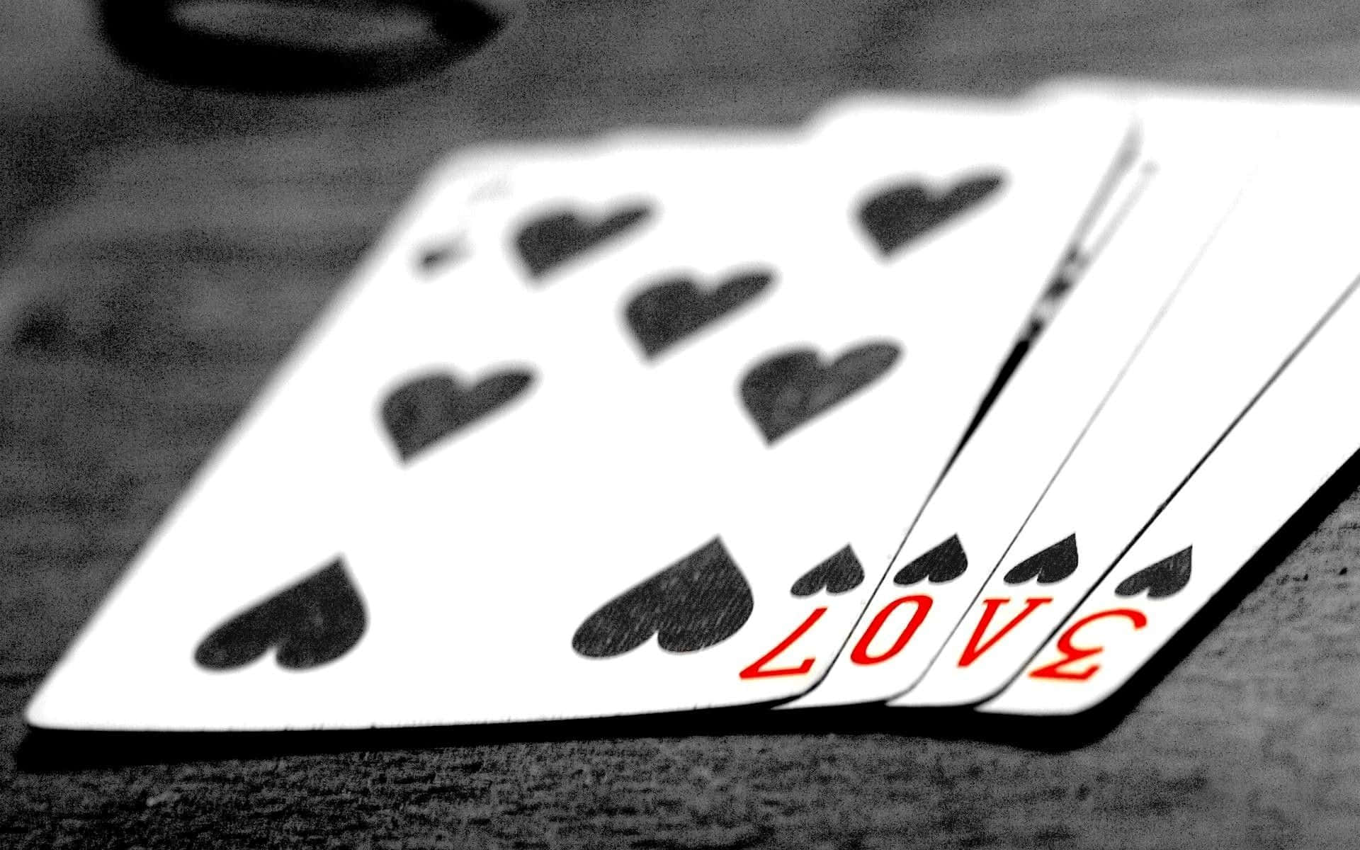 Card Games 桌布 壁紙 — 一副撲克牌扇形展開的黑白特寫，最底的一張牌上有紅色「LOVE」字樣。