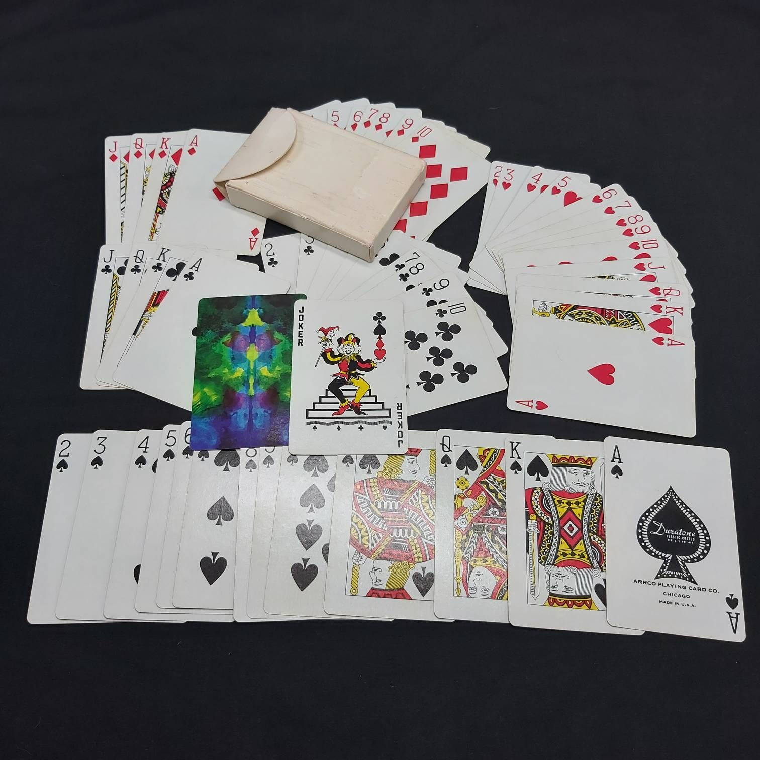 Playing Cards 桌布 壁紙 — 一副散落的復古撲克牌，帶有彩色小丑牌和一個樸素的盒子，放在黑色背景上。