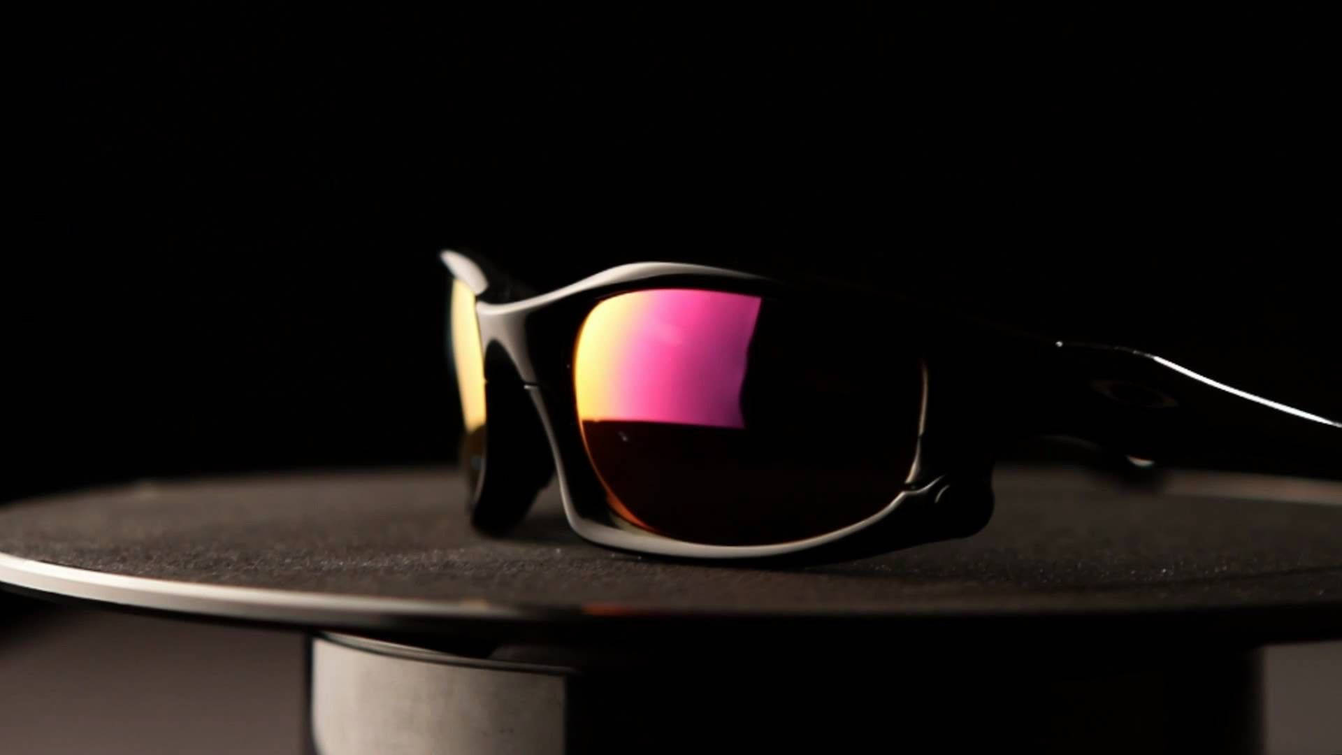 Sunglasses 桌布 壁紙 — 一副時尚的黑色太陽眼鏡，帶有虹彩粉紅色和金色鏡片，放置在黑色背景的深色紋理底座上。