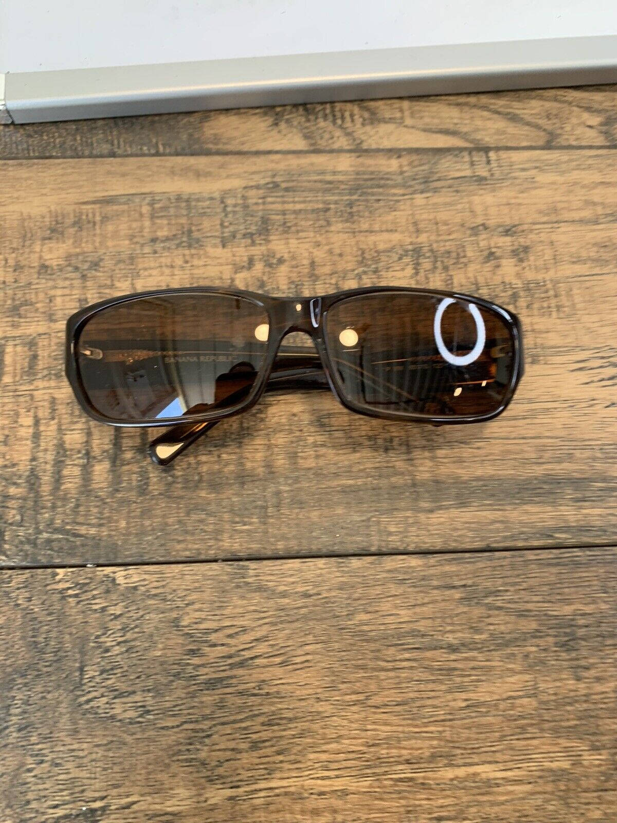 Sunglasses 桌布 壁紙 — 一副深棕色太陽眼鏡放在帶有明顯木紋和質感的質樸木質表面上。