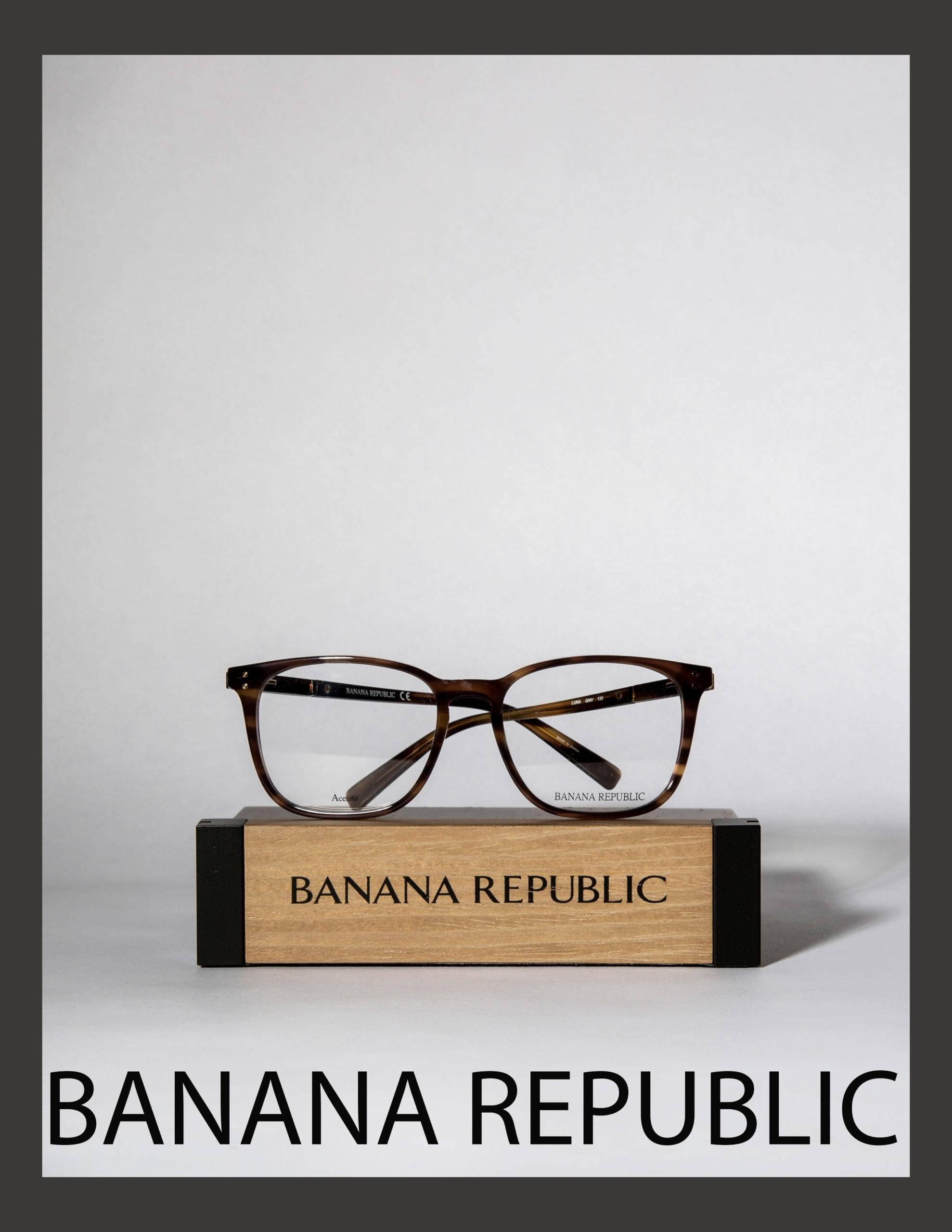 glasses 桌布 壁紙 — 一副玳瑁框眼鏡優雅地放置在一個有品牌的木製展示塊上，背景為簡約的白色。