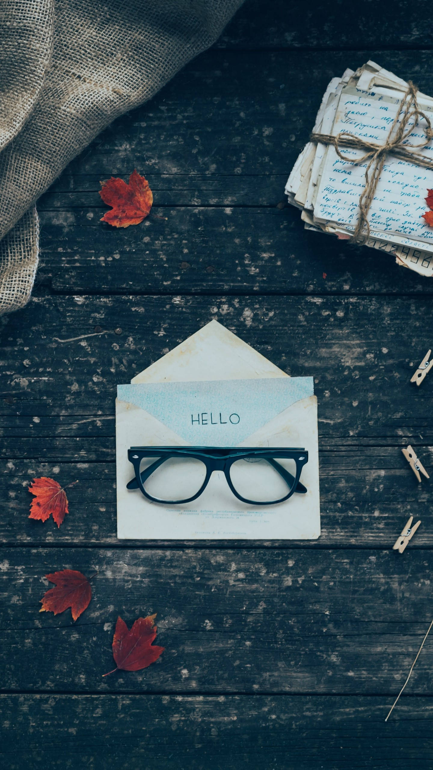 Hello 桌布 壁紙 — 一副眼鏡放在一個打開的信封上，信封上寫著hello，置於一張散落著秋葉和綁著信件的深色木桌上。