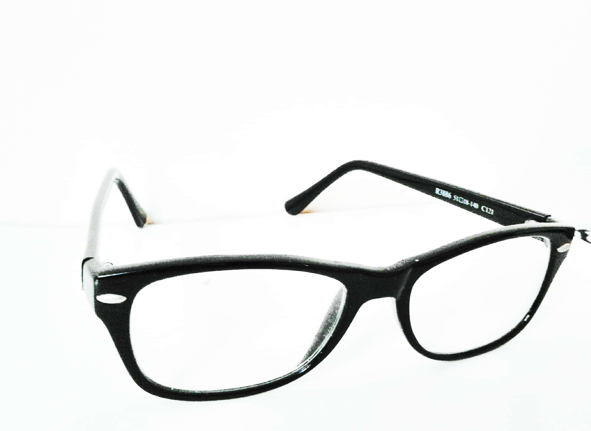 glasses 桌布 壁紙 — 一副經典黑色框眼鏡放在純白表面上，展現時尚設計與細緻金屬點綴。