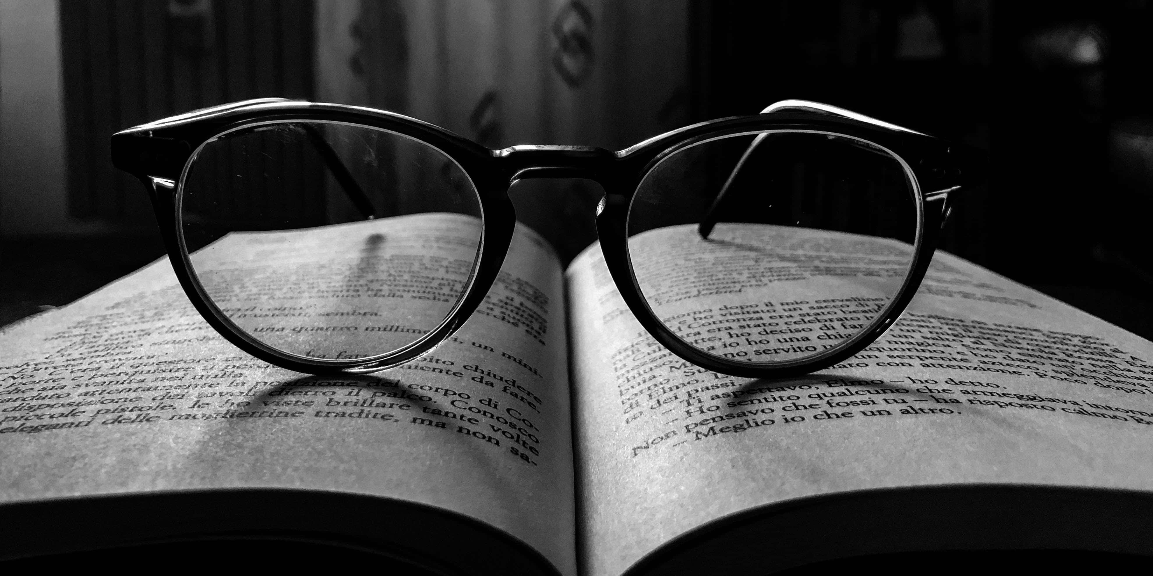 literature 桌布 壁紙 — 一副黑框眼鏡擱在一本打開的書上，以黑白拍攝，喚起安靜閱讀和知性平靜的感覺。