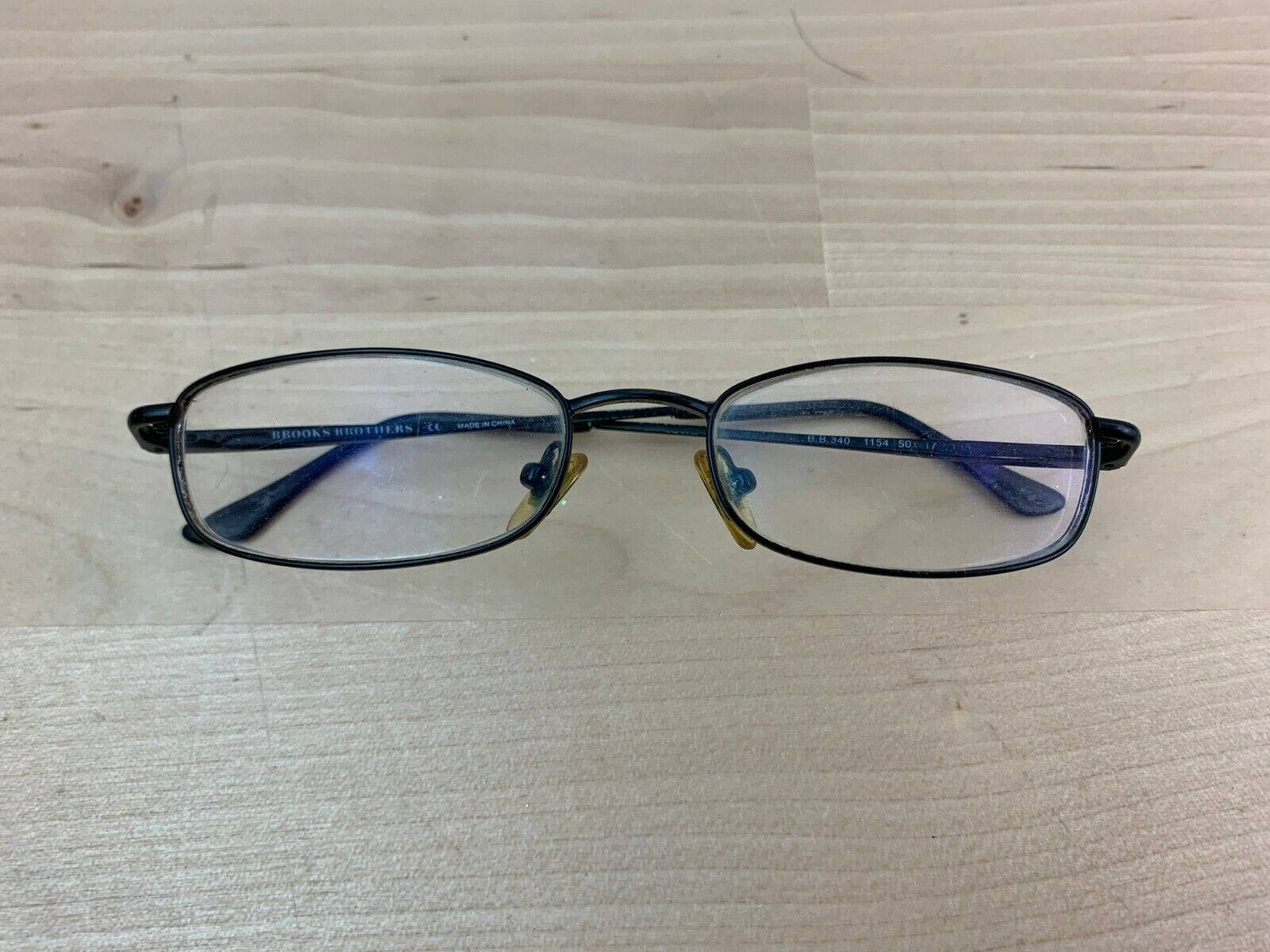 glasses 桌布 壁紙 — 一副黑色鏡框的Brooks Brothers閱讀眼鏡放在淺色木紋表面上。