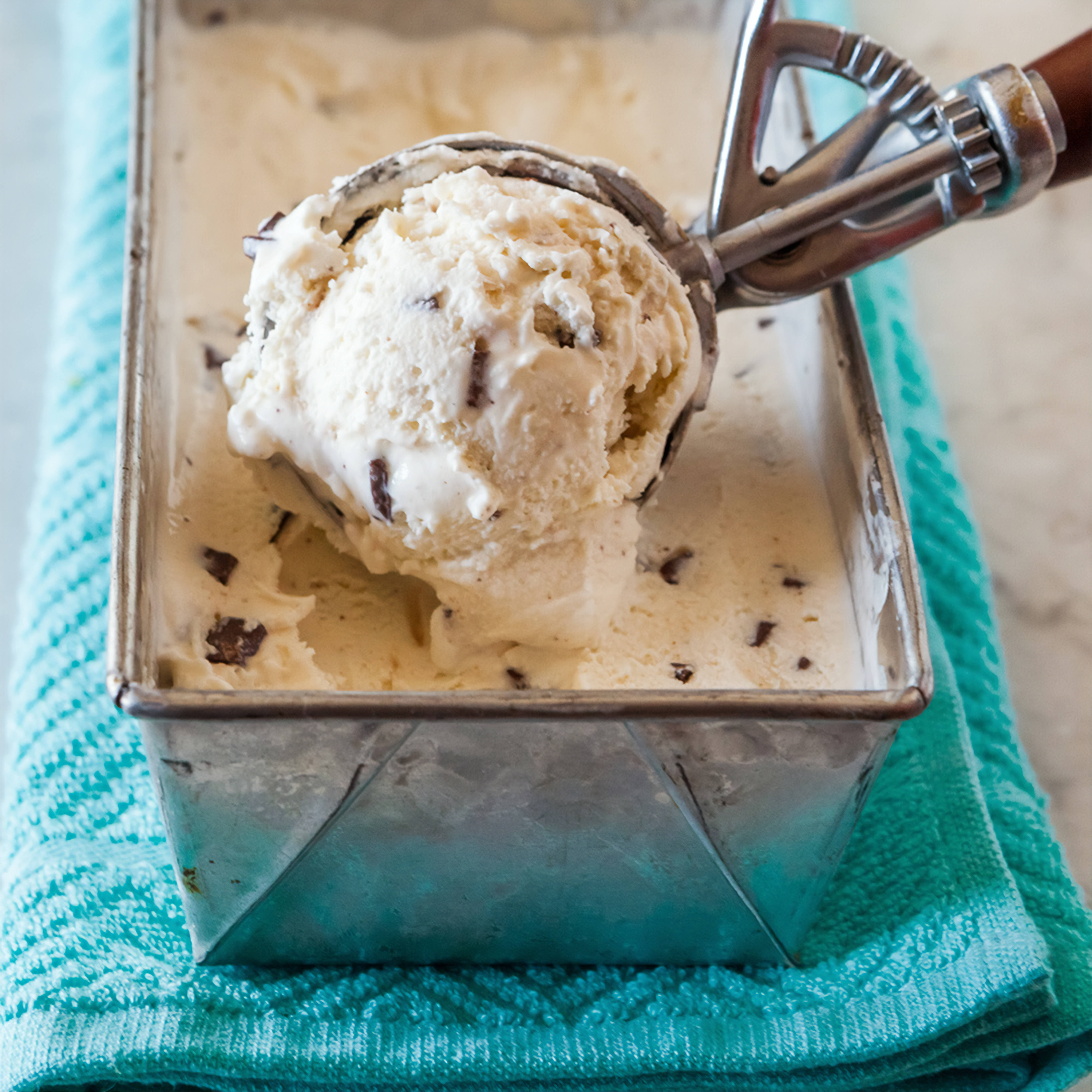 Ice Cream 桌布 壁紙 — 一勺奶油巧克力碎片冰淇淋從金屬麵包模中舀起，放在青綠色毛巾上。