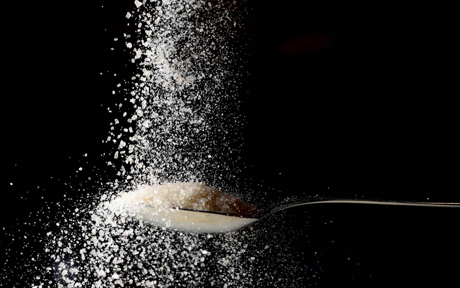 Food Photography 桌布 壁紙 — 一匙砂糖在純黑背景上爆裂成閃爍的瀑布。