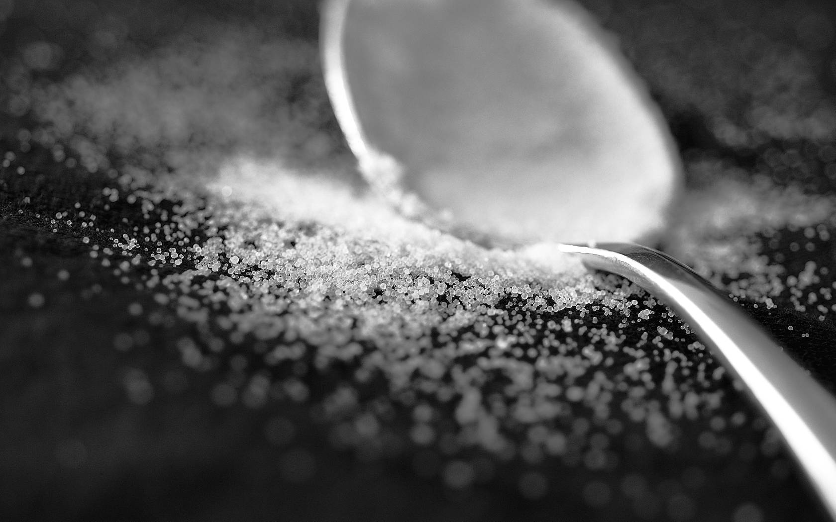 Sugar 桌布 壁紙 — 一匙砂糖從湯匙灑落到深色紋理表面的黑白特寫。