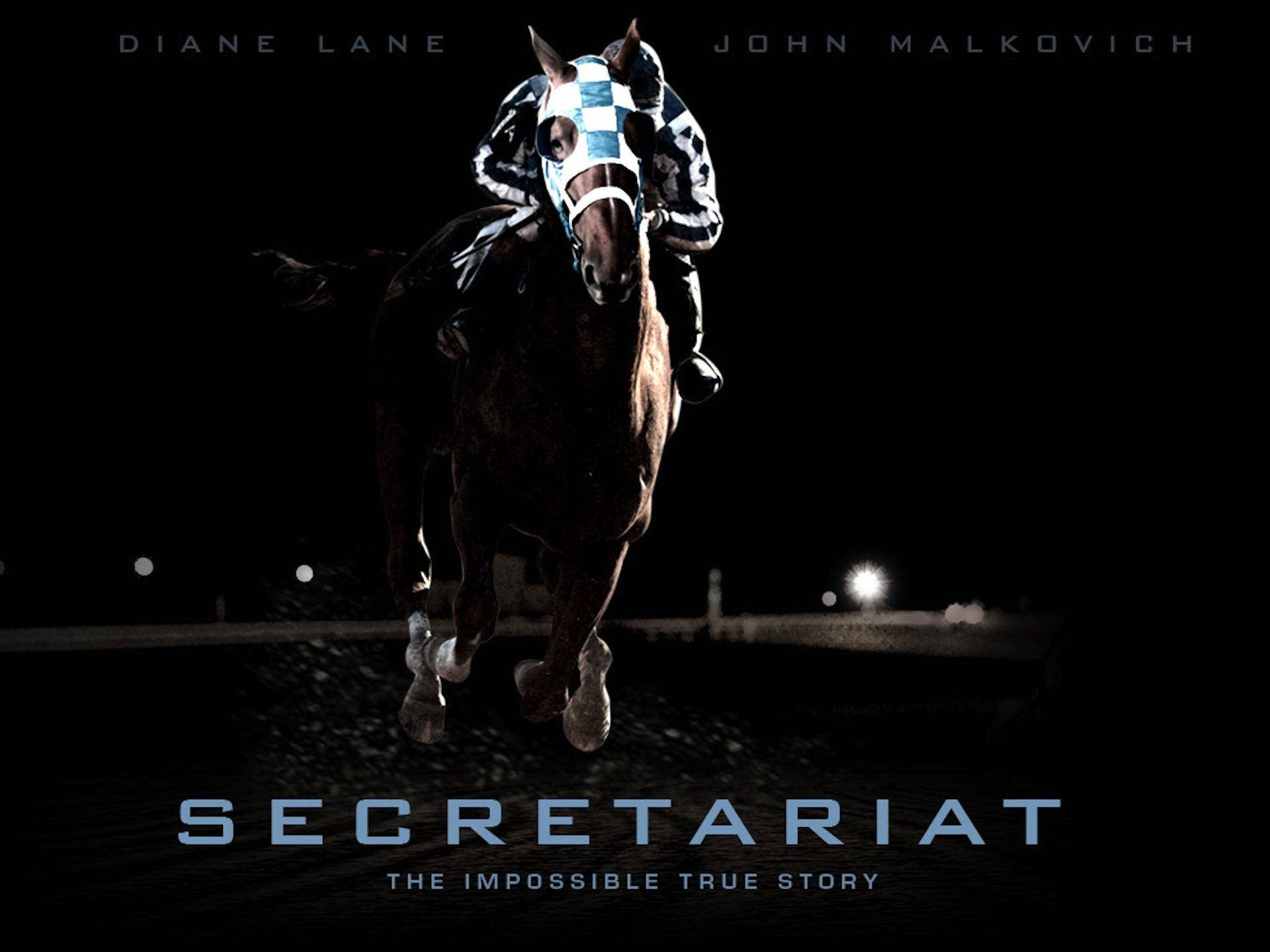 Secretariat 桌布 壁紙 — 一匹強壯的賽馬與騎師在黑色背景下，於明亮的賽道燈光下夜間奔馳。