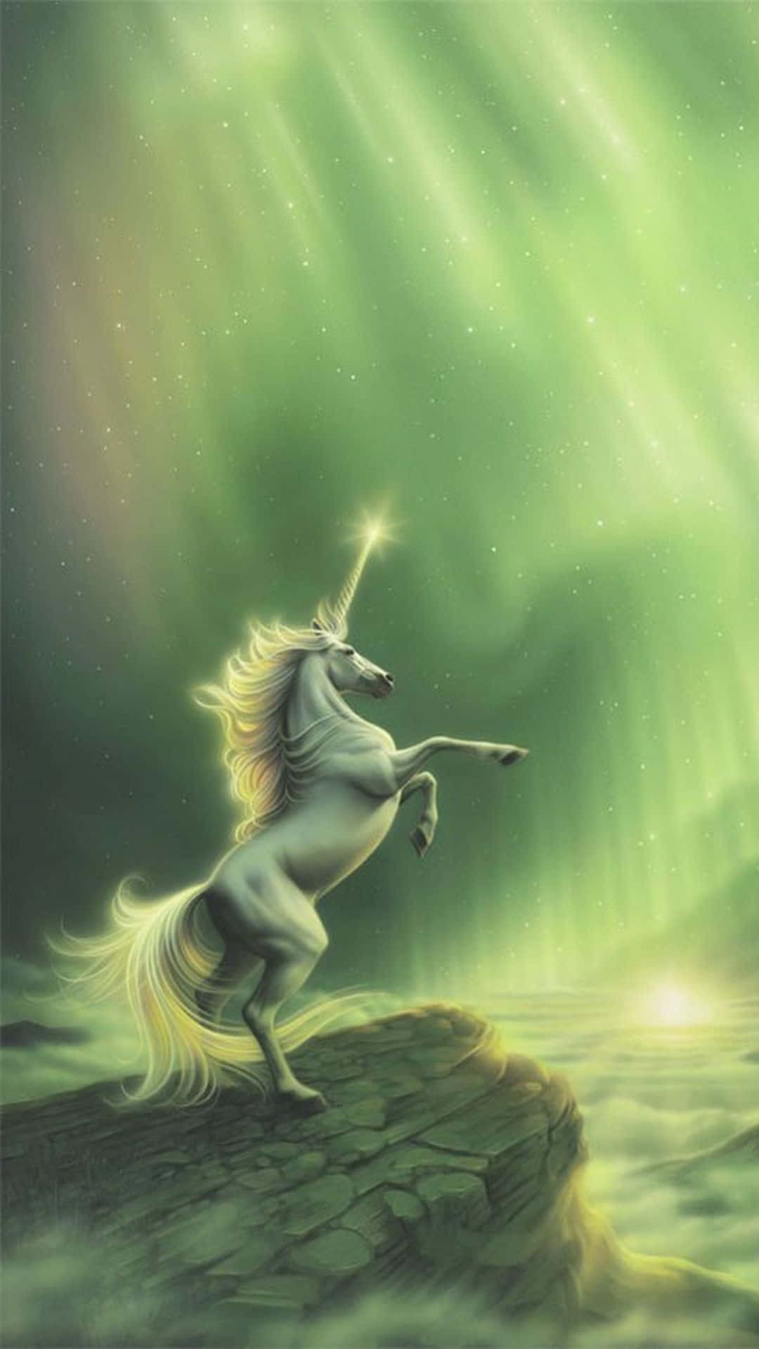 獨角獸 桌布 壁紙 — 一匹雄偉的白色獨角獸在岩石懸崖上驕傲地揚起，下方是充滿活力的綠色北極光，散發著天國的光芒。