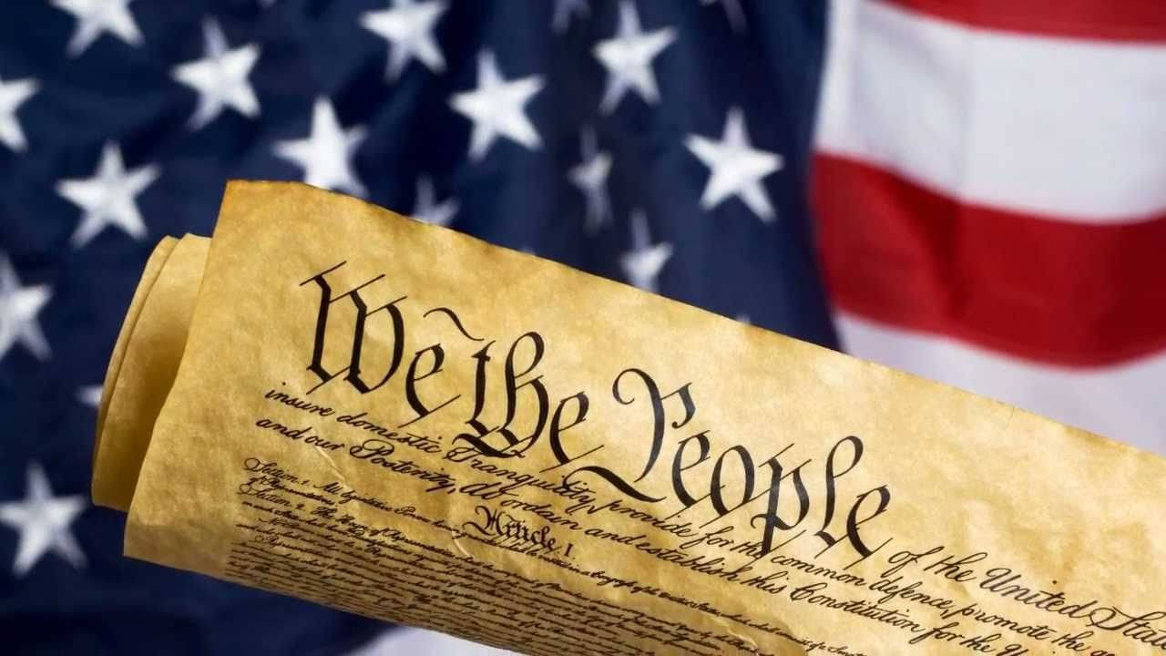Patriotic 桌布 壁紙 — 一卷美國憲法羊皮紙，上面有優雅字體的「We the People」，背景是模糊的美國國旗。