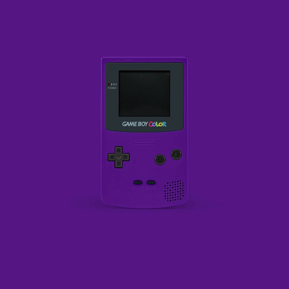 game 桌布 壁紙 — 一台充滿活力的紫色 Game Boy Color 主機，置中於純紫色背景上，帶有柔和陰影。