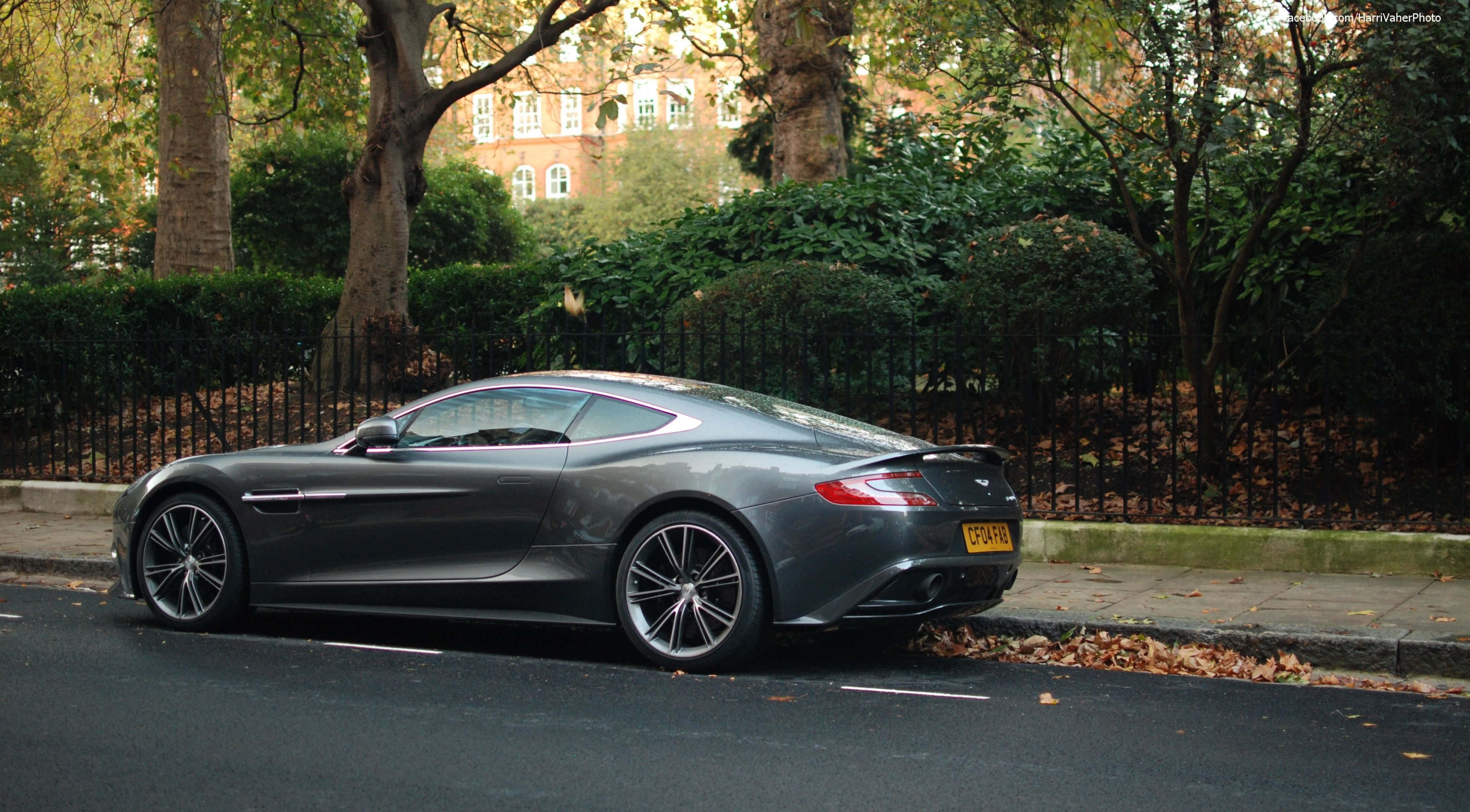 Aston Martin Vanquish 桌布 壁紙 — 一台型格啞灰色Aston Martin Vanquish停泊在樹木林立、落葉滿地的秋日街道上。
