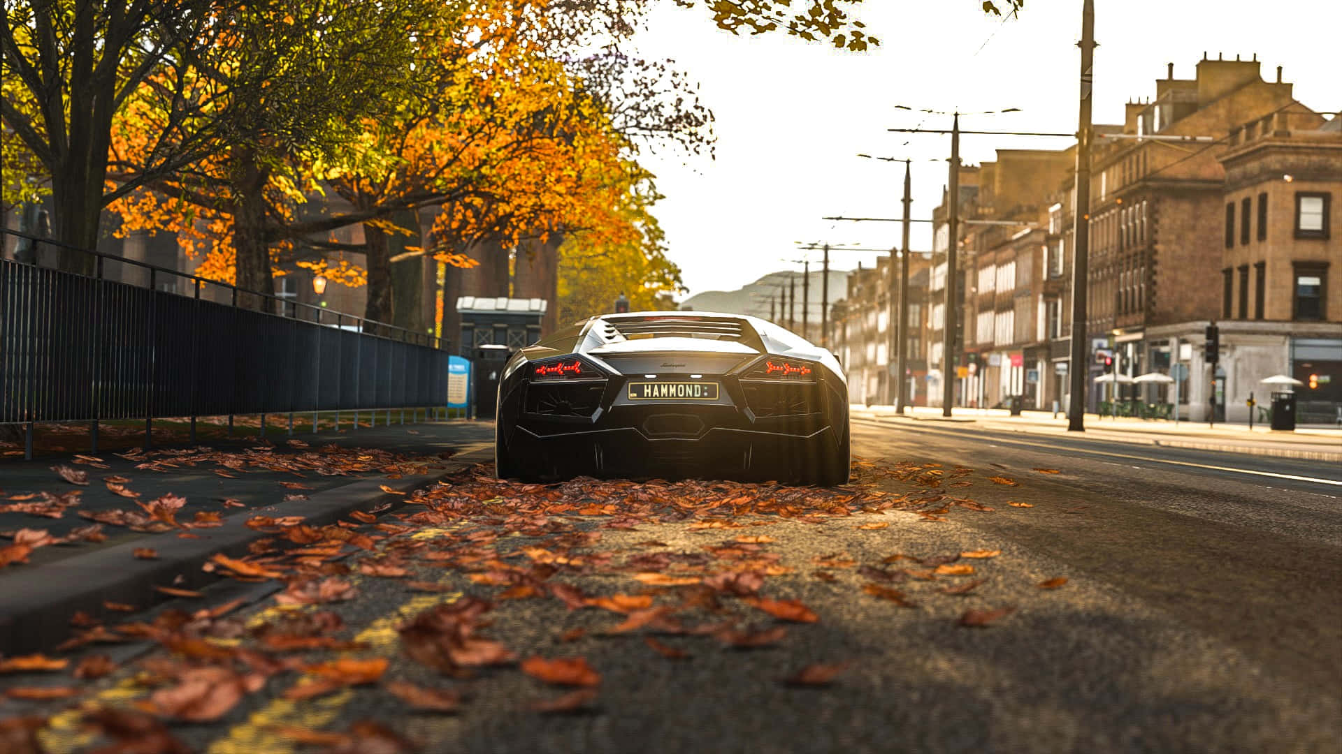 HD Forza Horizon 4 桌布 壁紙 — 一台型格黑色藍寶堅尼Aventador停泊在鋪滿落葉的都市街道上，沐浴在金色的秋日陽光中。
