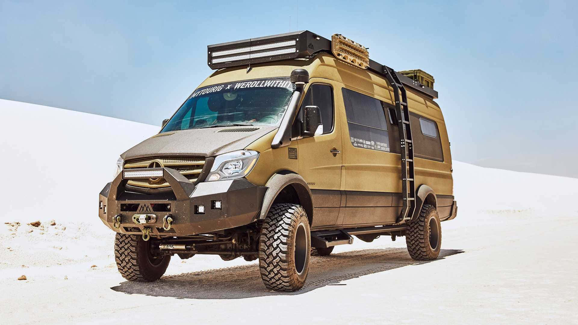 Mercedes Benz Sprinter 桌布 壁紙 — 一台堅固的金棕色越野露營車，配備超大輪胎和車頂行李架，在晴朗藍天下矗立於廣闊的白色鹽灘上。