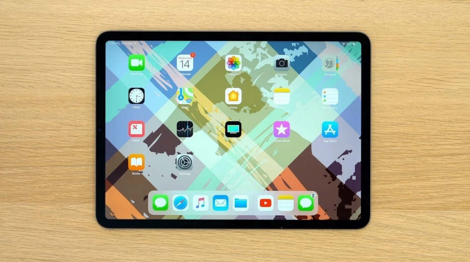 iPad 桌布 壁紙 — 一台帶有彩色應用程式圖標的平板電腦放置在淺色木質表面上，顯示充滿活力的抽象桌布。