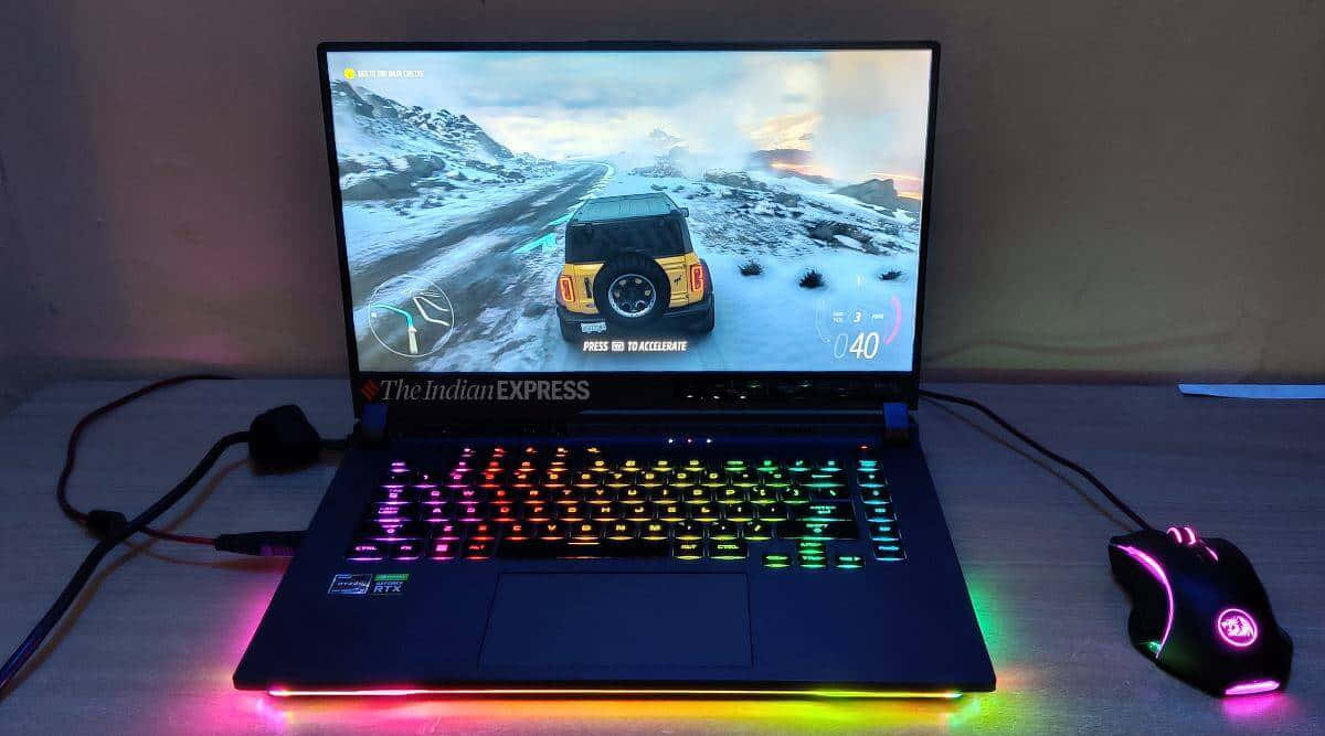 華碩 ROG 桌布 壁紙 — 一台帶有彩虹背光鍵的遊戲筆記型電腦顯示一個雪地越野賽車遊戲，旁邊有一個發光的滑鼠。