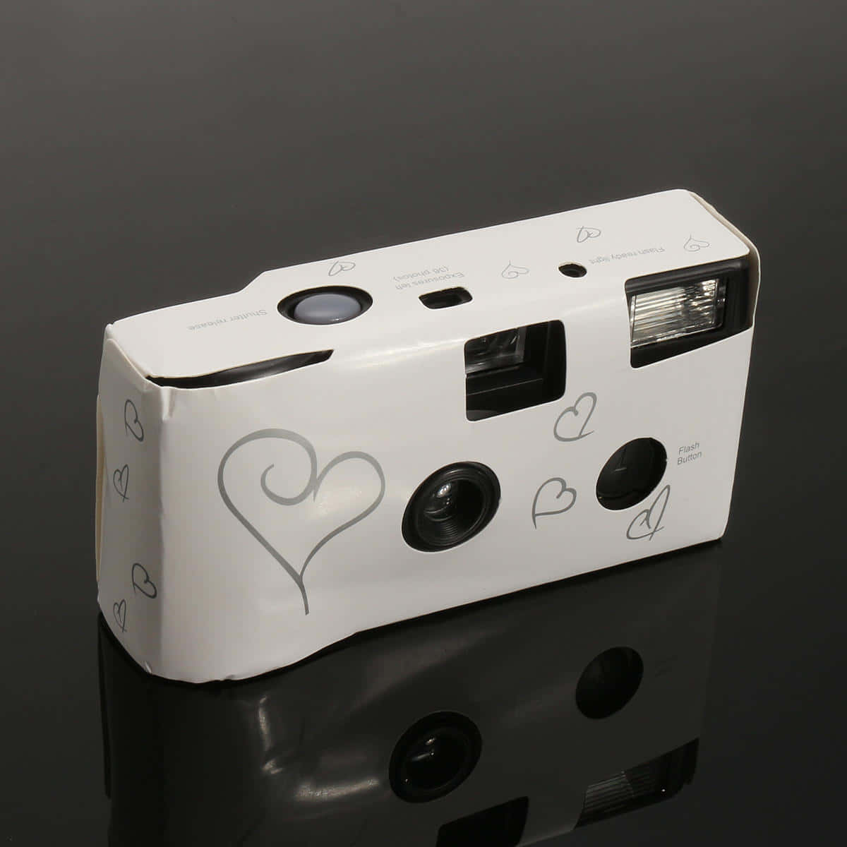Disposable Camera 桌布 壁紙 — 一台帶有心形貼紙的白色拍立得相機放在光滑的黑色表面上，投射出清晰的倒影。