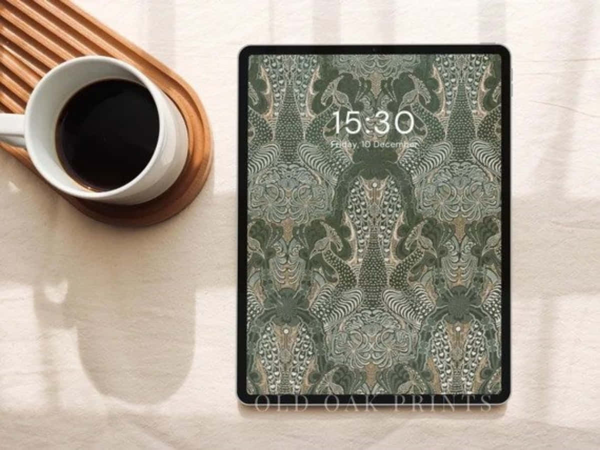 美學 iPad 壁紙 桌布 壁紙 — 一台平板電腦帶有複雜的綠色和米色圖案壁紙，放在木托盤上，旁邊有一個白色咖啡杯。