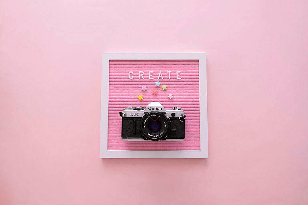 Pastel Pink Aesthetic 桌布 壁紙 — 一台復古Canon相機放在粉紅色氈板上，板上顯示CREATE字樣及彩色星星。