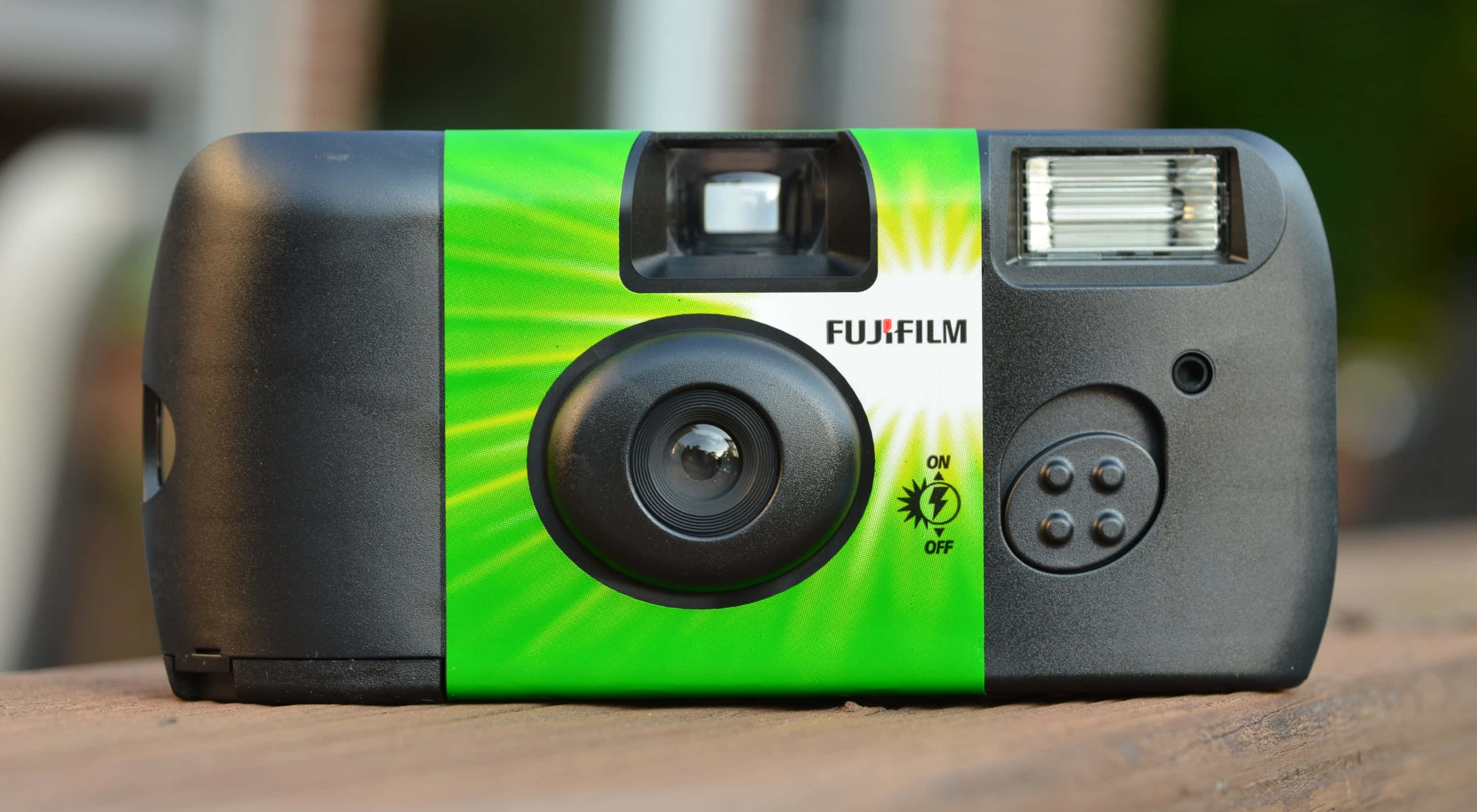 Disposable Camera 桌布 壁紙 — 一台復古Fujifilm輕便相機，帶有明亮的綠色太陽光線設計，放置在木質表面上。