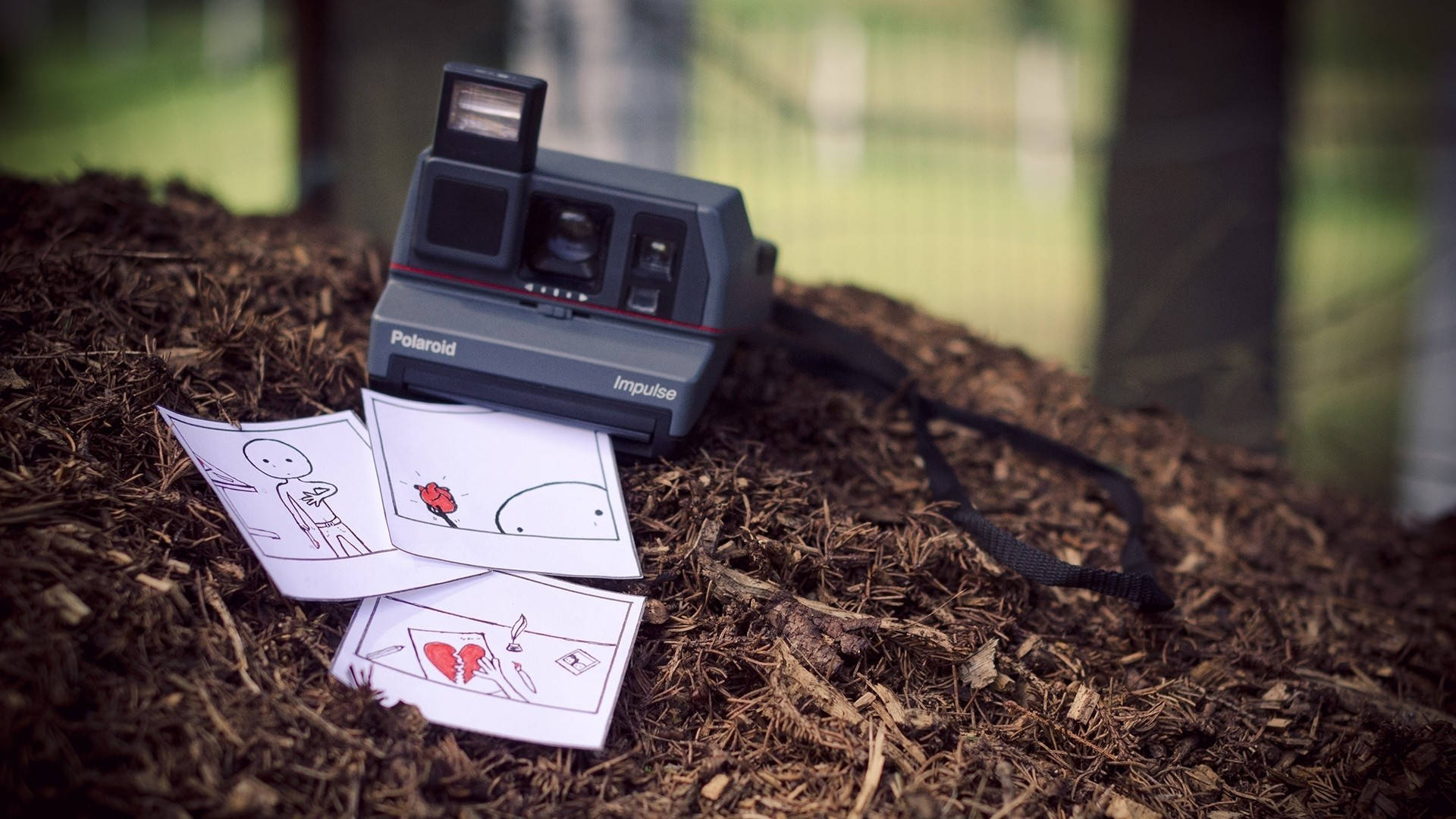 拍立得 桌布 壁紙 — 一台復古Polaroid Impulse相機放在覆蓋物上，旁邊有手繪漫畫條，描繪簡單的火柴人圖案和一顆破碎的心。