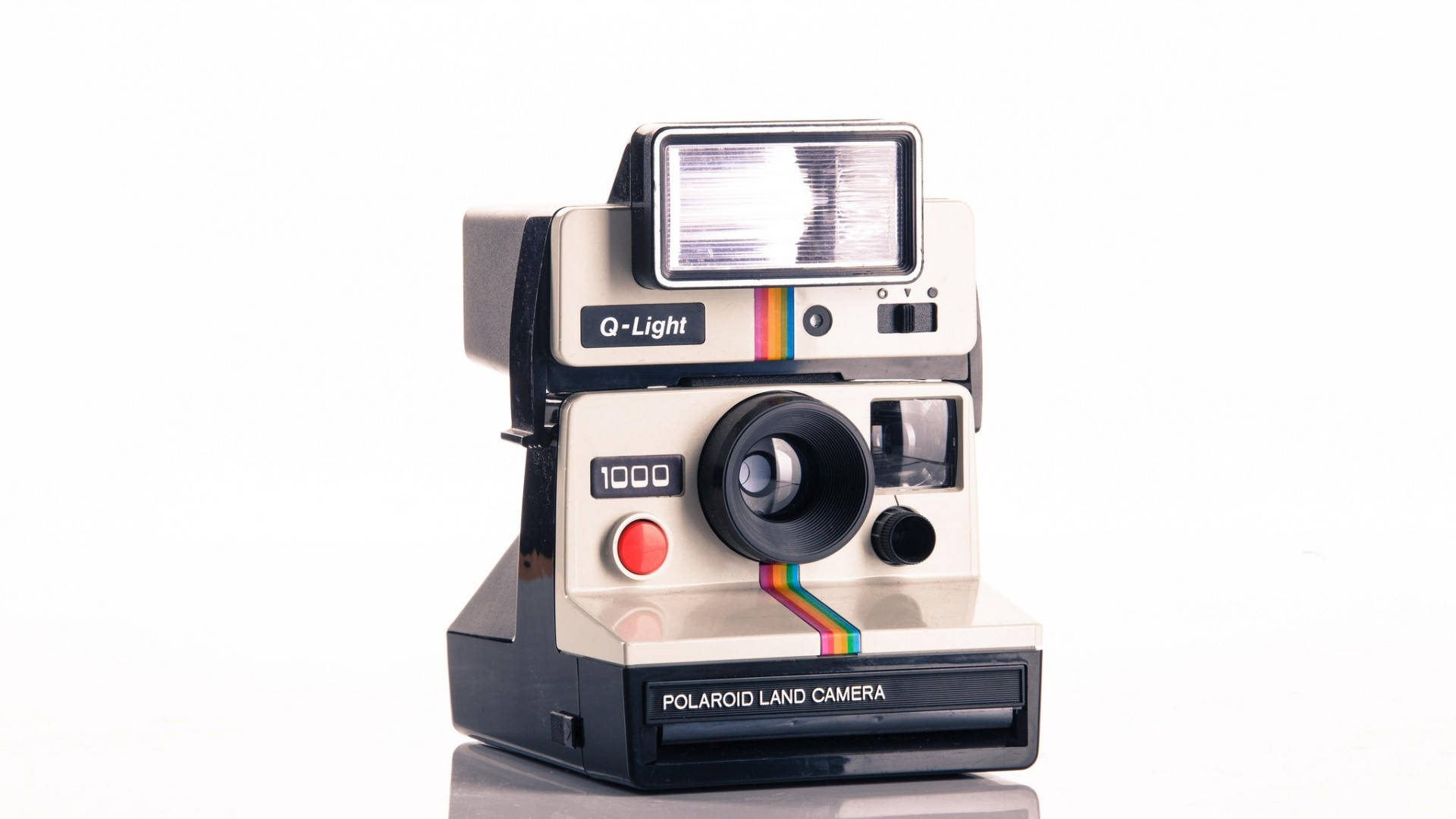 拍立得 桌布 壁紙 — 一台復古Polaroid Land Camera 1000相機搭配Q-Light閃光燈，孤立地放置在白色反光表面上。