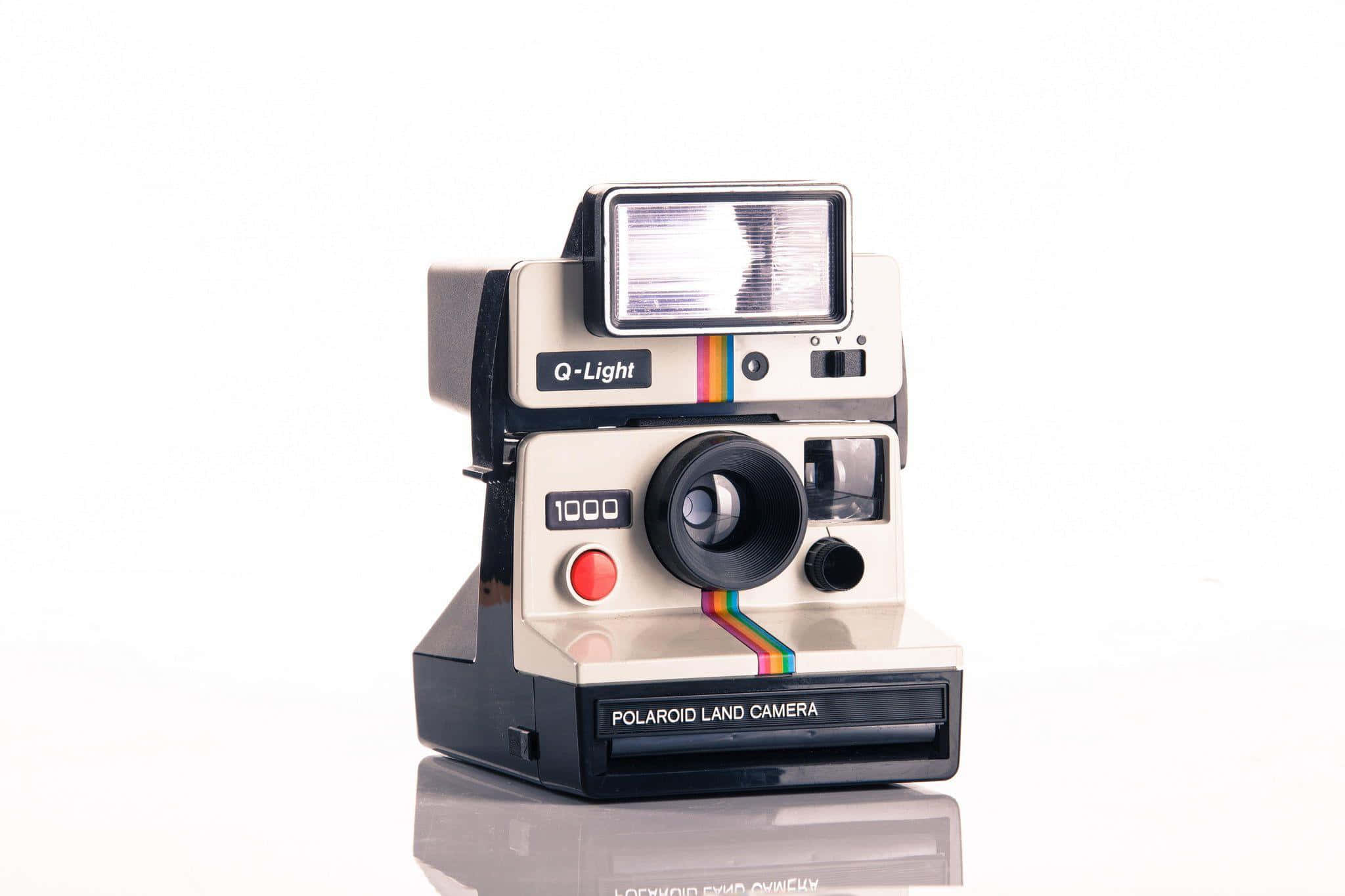 拍立得 桌布 壁紙 — 一台復古Polaroid Land Camera 1000相機連Q-Light閃光燈，孤立放置在反光白色表面上。