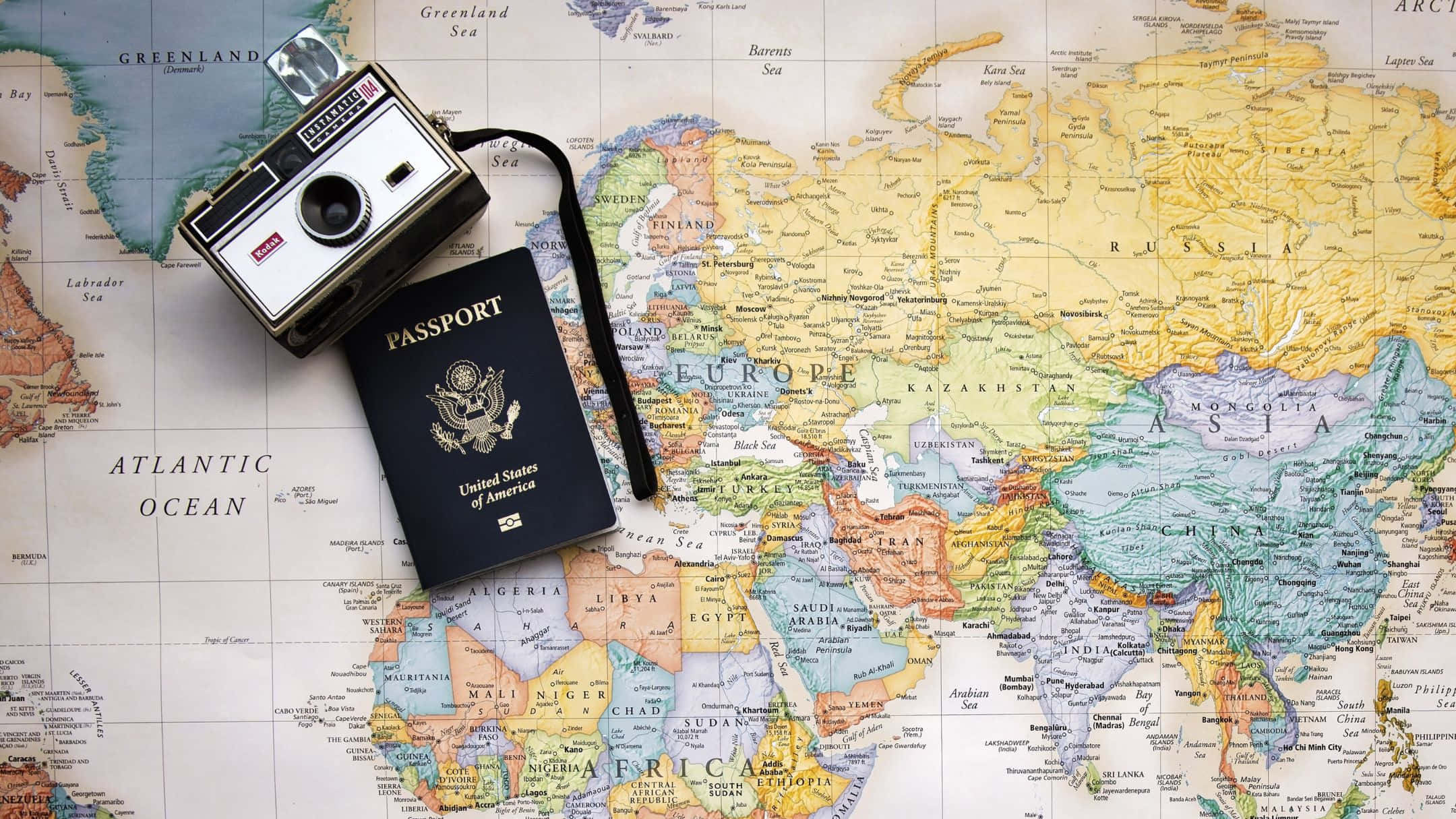 Passport 桌布 壁紙 — 一台復古相機和美國護照放在色彩繽紛的世界地圖上，突顯全球旅行準備就緒。