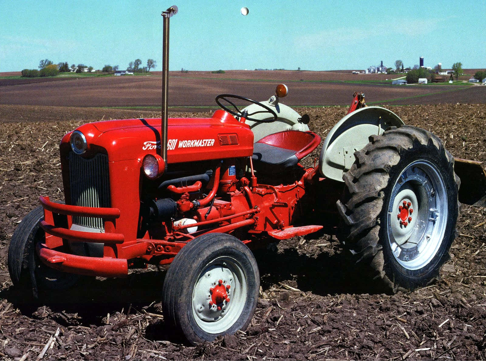 Tractor 桌布 壁紙 — 一台復古紅色福特500 Workmaster拖拉機，在晴朗的藍天下，驕傲地矗立在剛翻耕過的棕色田野中。