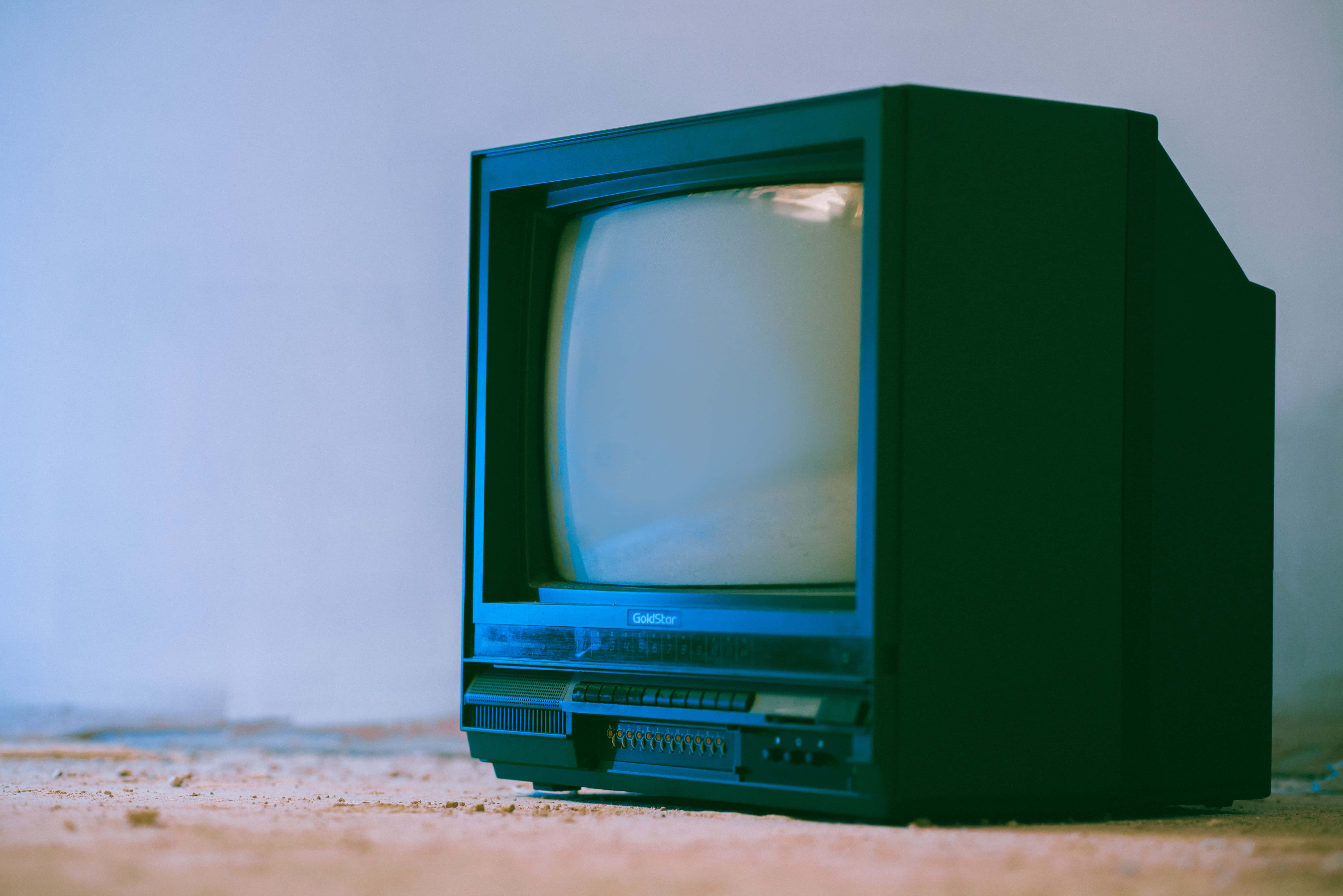 tv 桌布 壁紙 — 一台復古綠色CRT電視獨自放在塵土飛揚的地板上，靠著普通牆壁，在冷藍色燈光下。