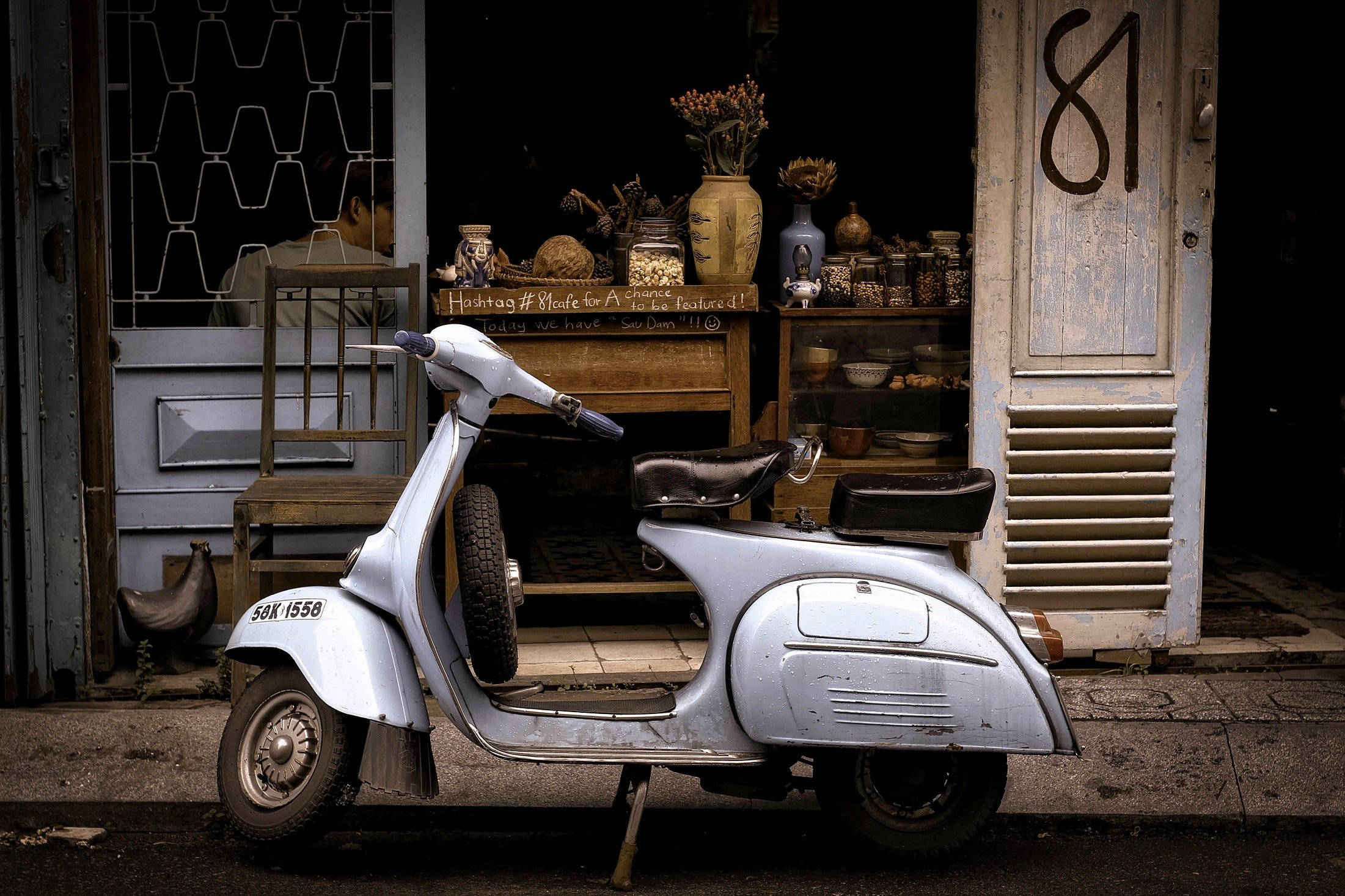 scooter 桌布 壁紙 — 一台復古銀色機車停放在鄉村風格店鋪外，店內有木架和乾燥花。