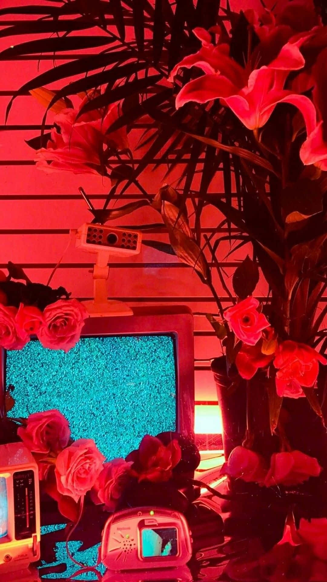 Aesthetic Red 桌布 壁紙 — 一台復古電視，螢幕顯示雪花，被紅花和棕櫚葉環繞，處於強烈紅光下。