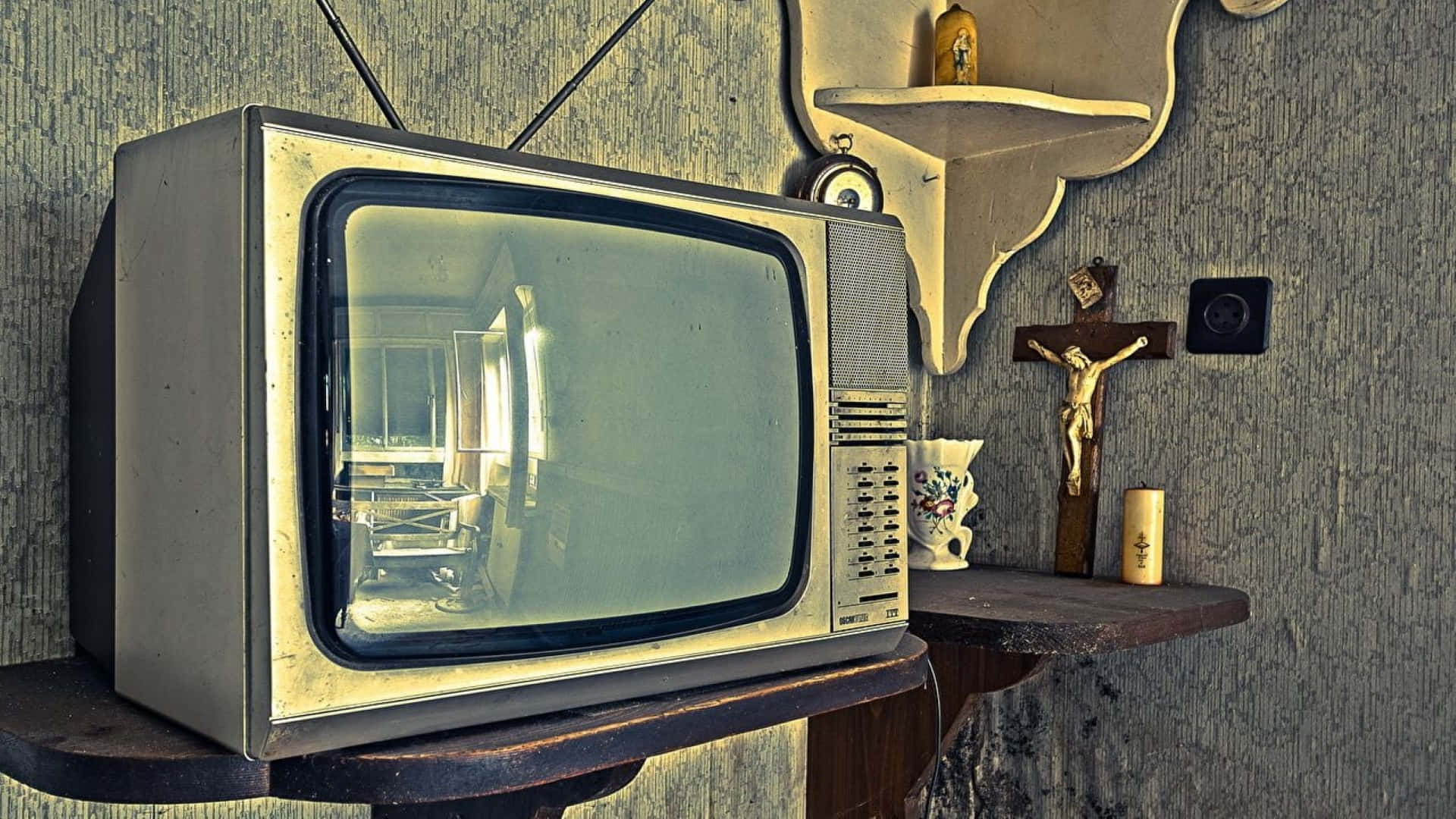 Television Set 桌布 壁紙 — 一台復古電視機放在木架上，旁邊有十字架和蠟燭，房間牆壁有紋理。