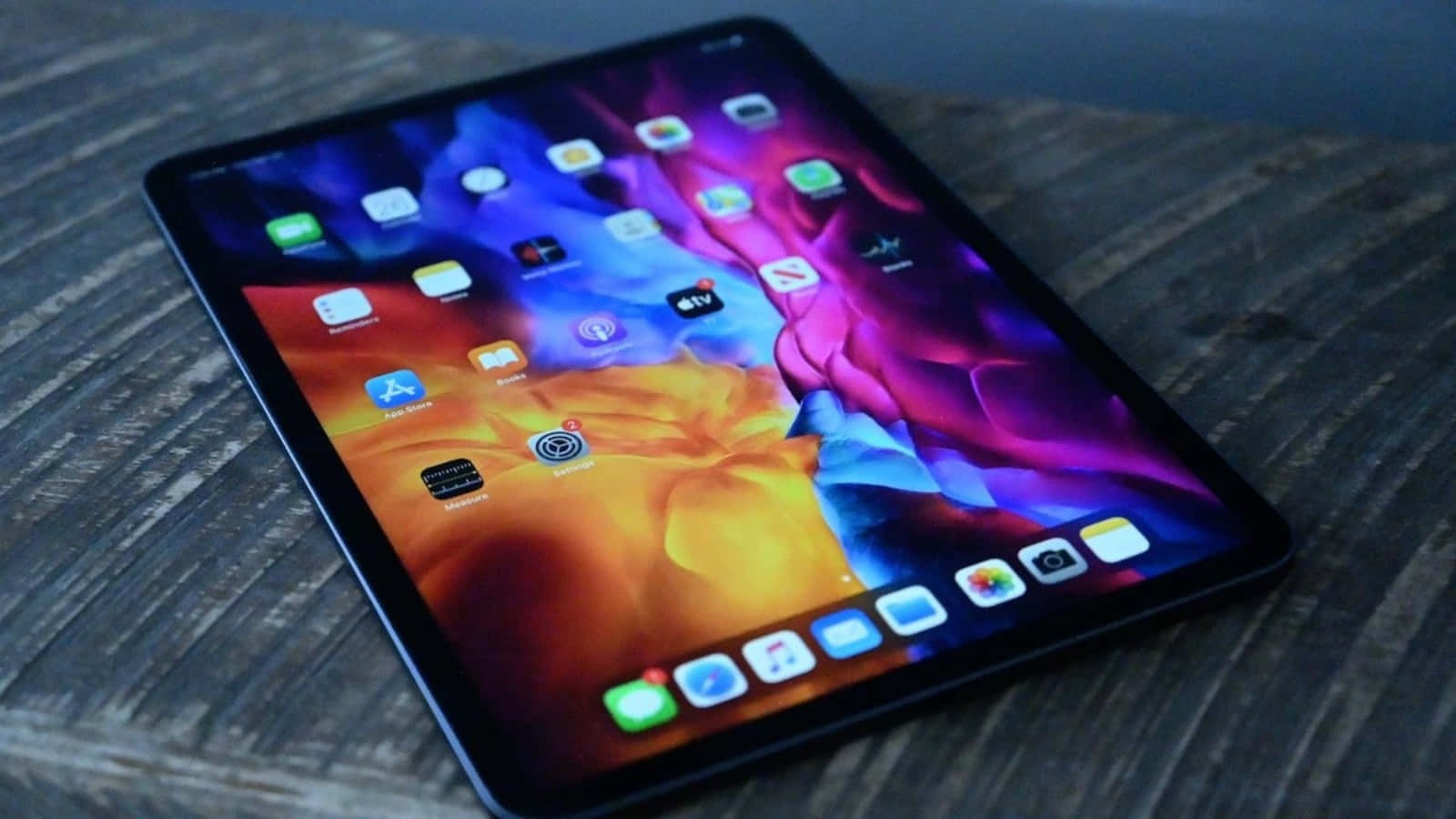 iPad 桌布 壁紙 — 一台時尚平板電腦，帶有鮮豔的抽象桌布，放置在紋理木質表面上。