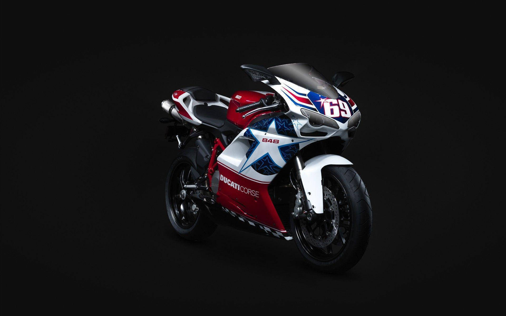  壁紙 — 一台時尚的Ducati 848機車，帶有紅白藍星形設計，矗立在純黑背景上。