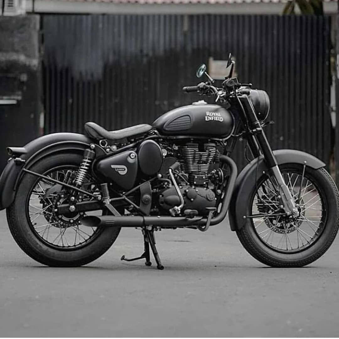 Royal 桌布 壁紙 — 一台時尚的啞光黑色 Royal Enfield 摩托車以側腳架支撐，停在波紋金屬背景前。