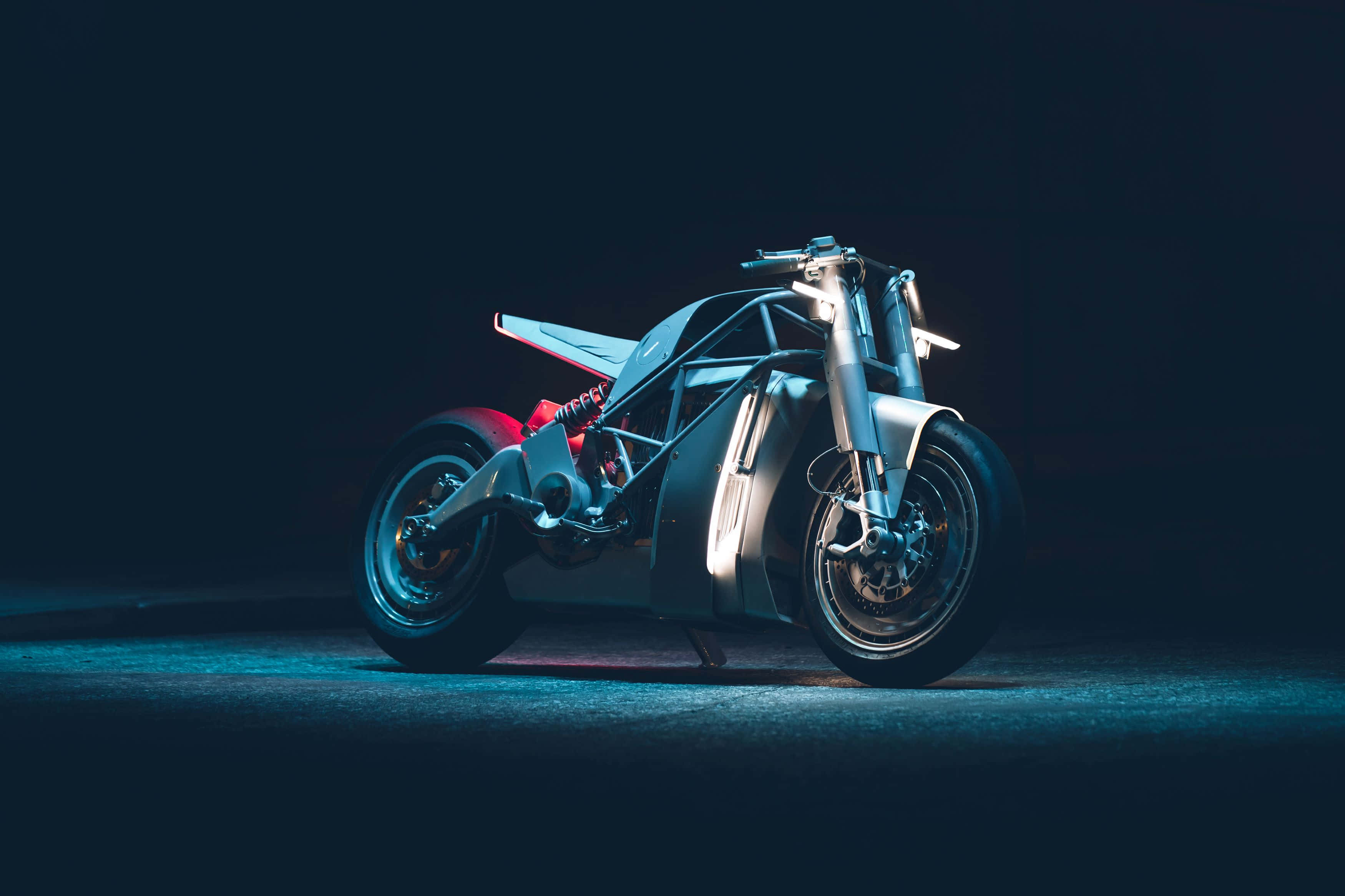 Electric Bike 桌布 壁紙 — 一台時尚的未來摩托車在黑暗的攝影棚背景下，在戲劇性的藍色燈光下發光。